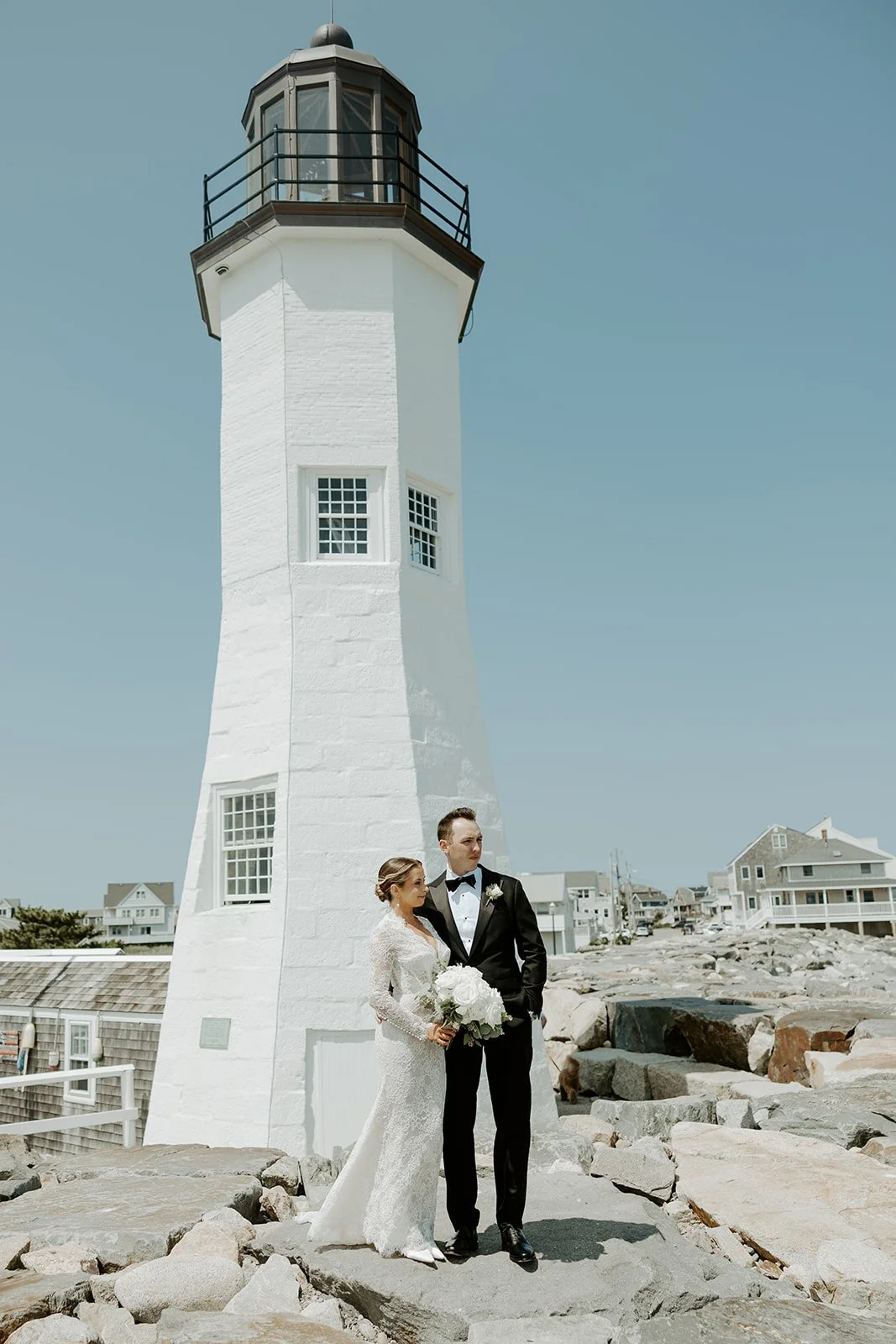 A bride and groom posing for wedding photos at a lighthouse