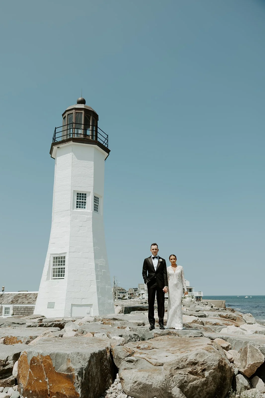 A bride and groom posing for wedding photos at a lighthouse