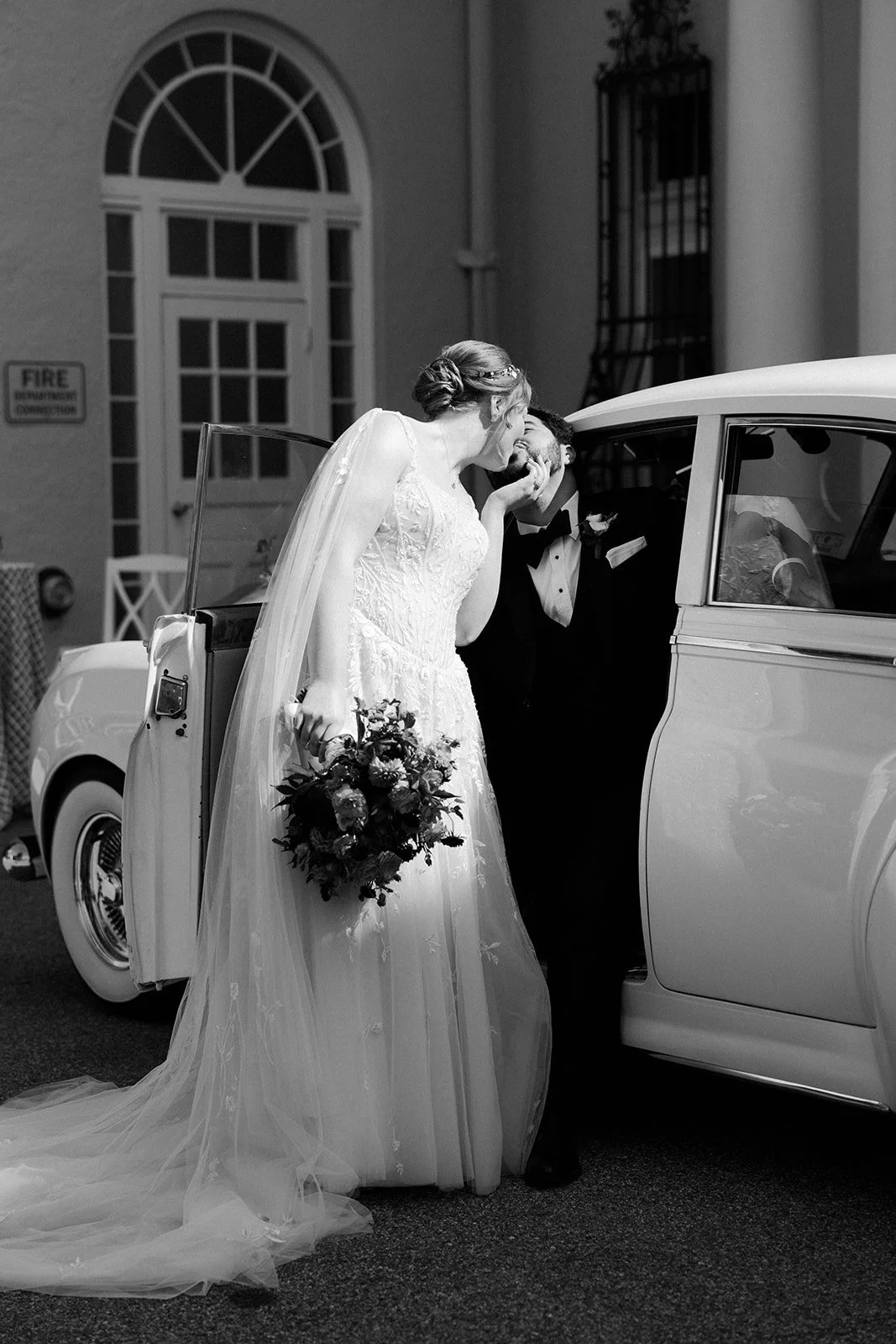 A bride and groom taking photos in a vintage car