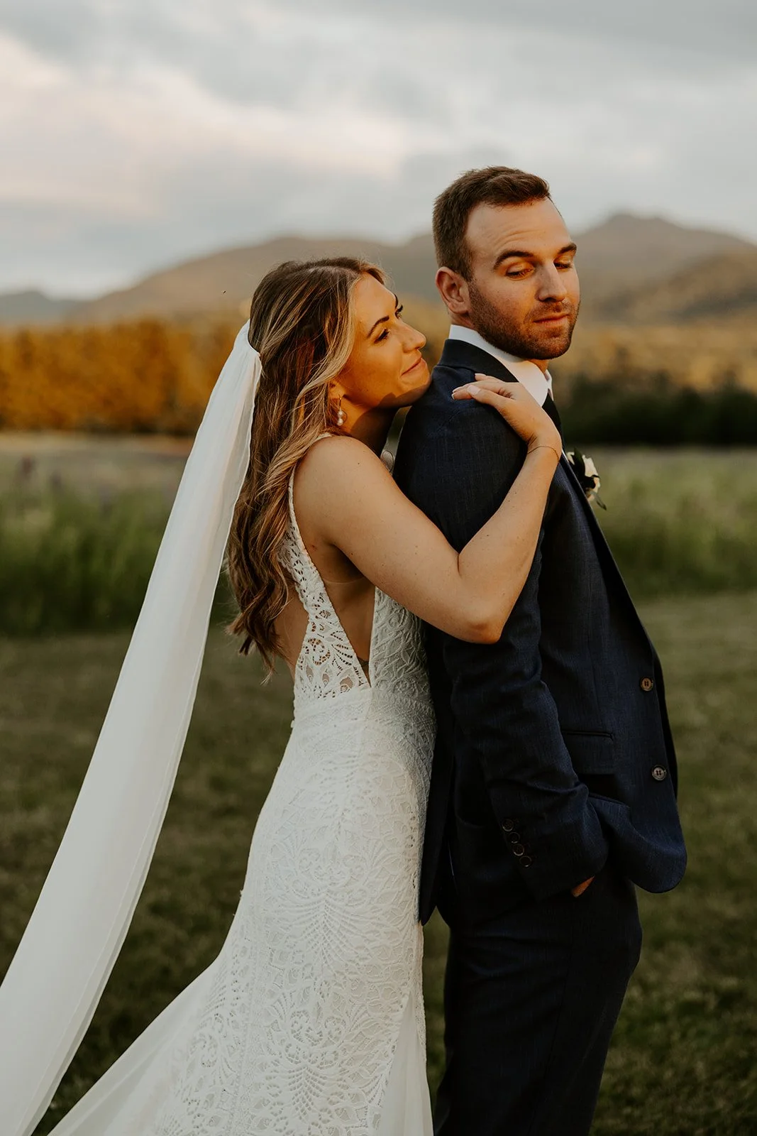 A bride and groom taking sunset photos in front of the Vermont mountains
