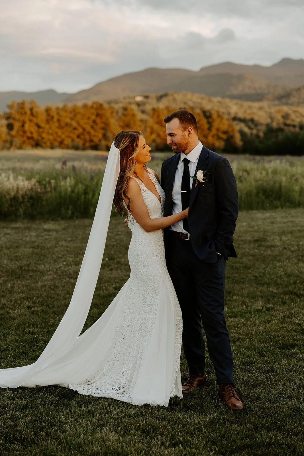 A bride and groom taking sunset photos in front of the Vermont mountains