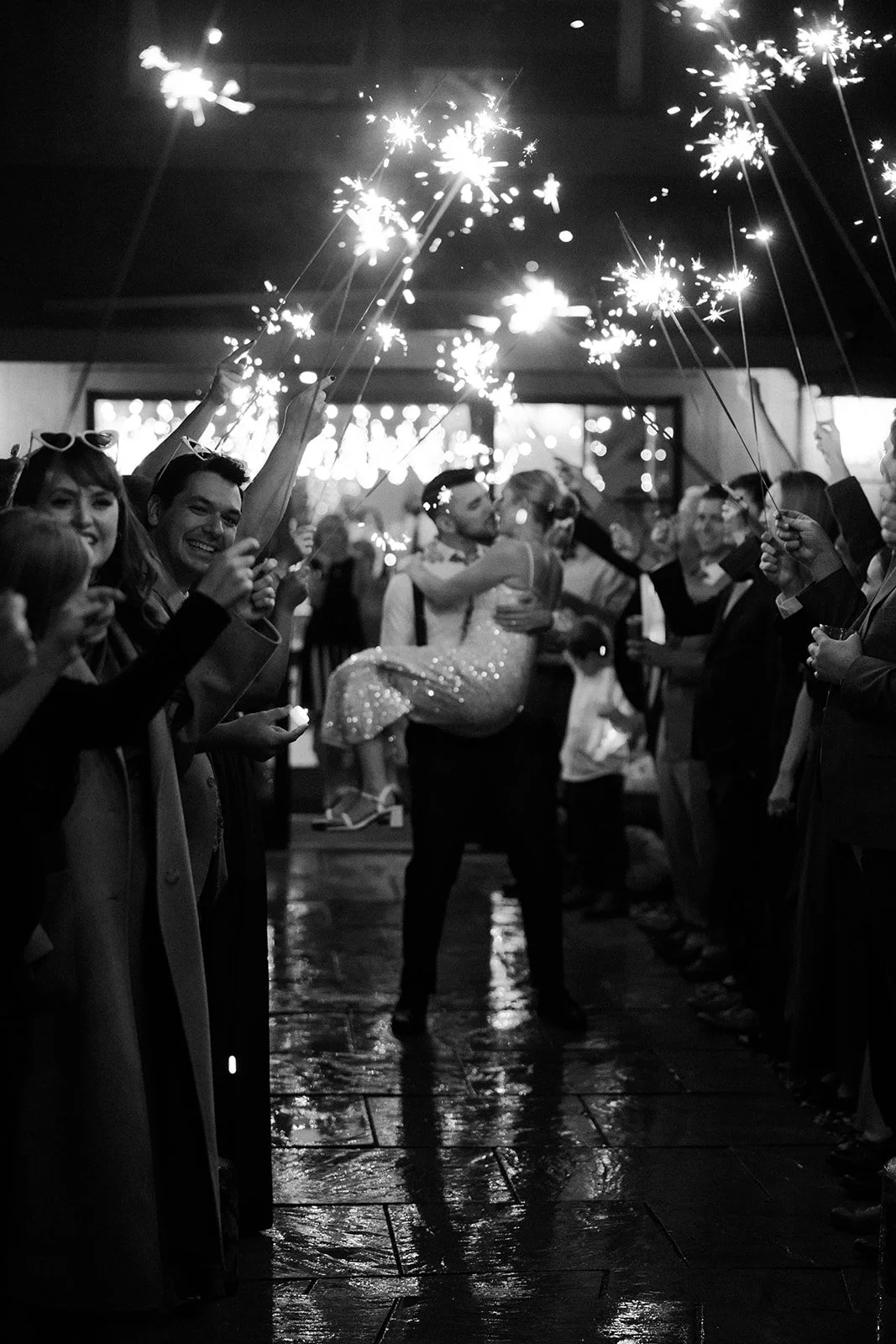 A bride and groom leaving their wedding through a sparkler exit