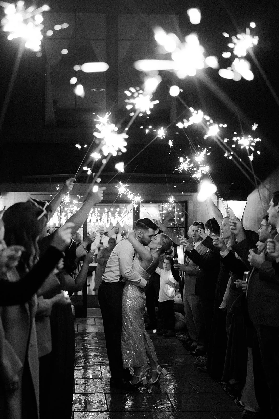A bride and groom leaving their wedding through a sparkler exit