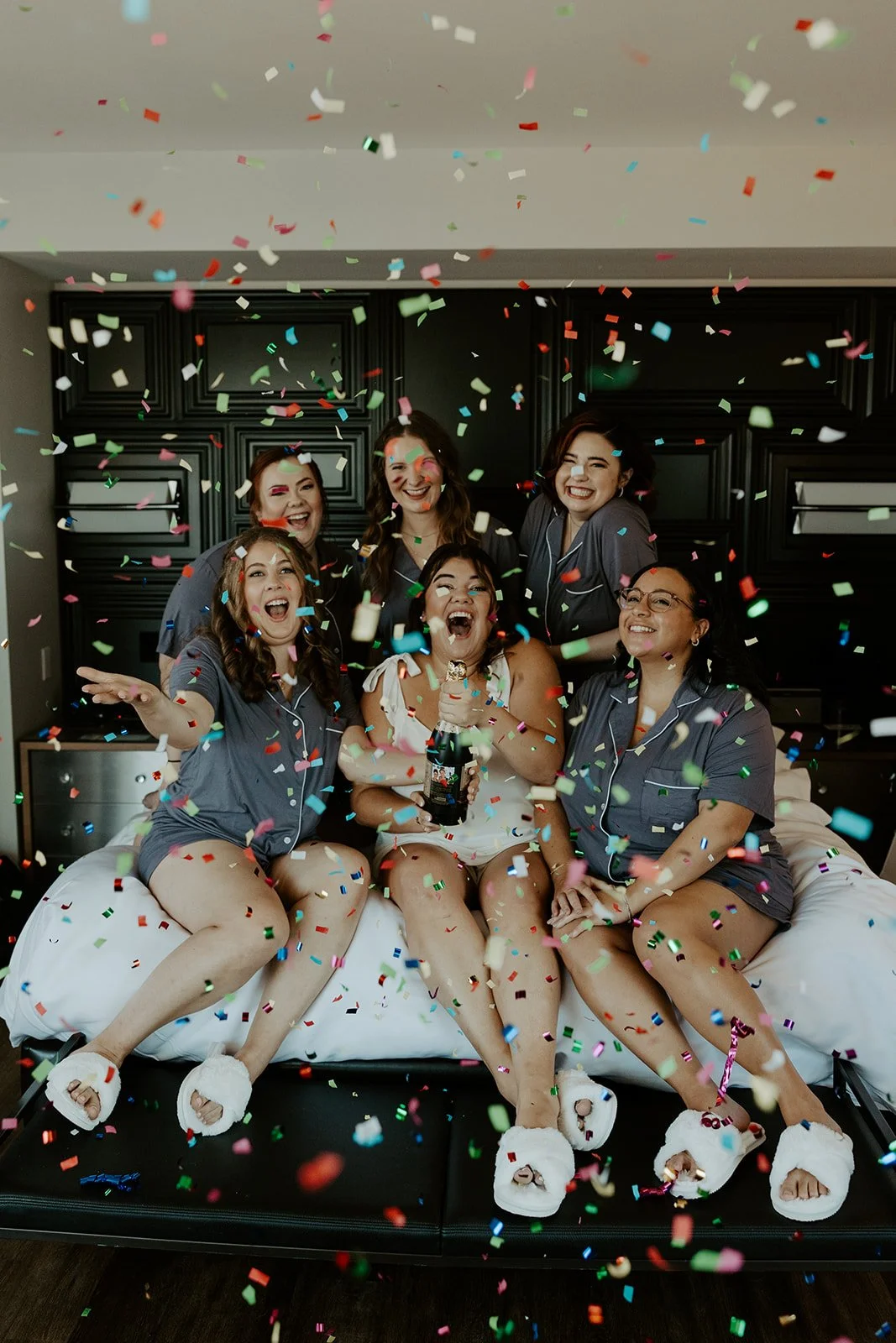 A bride and bridesmaids taking getting ready wedding photos at a hotel with confetti