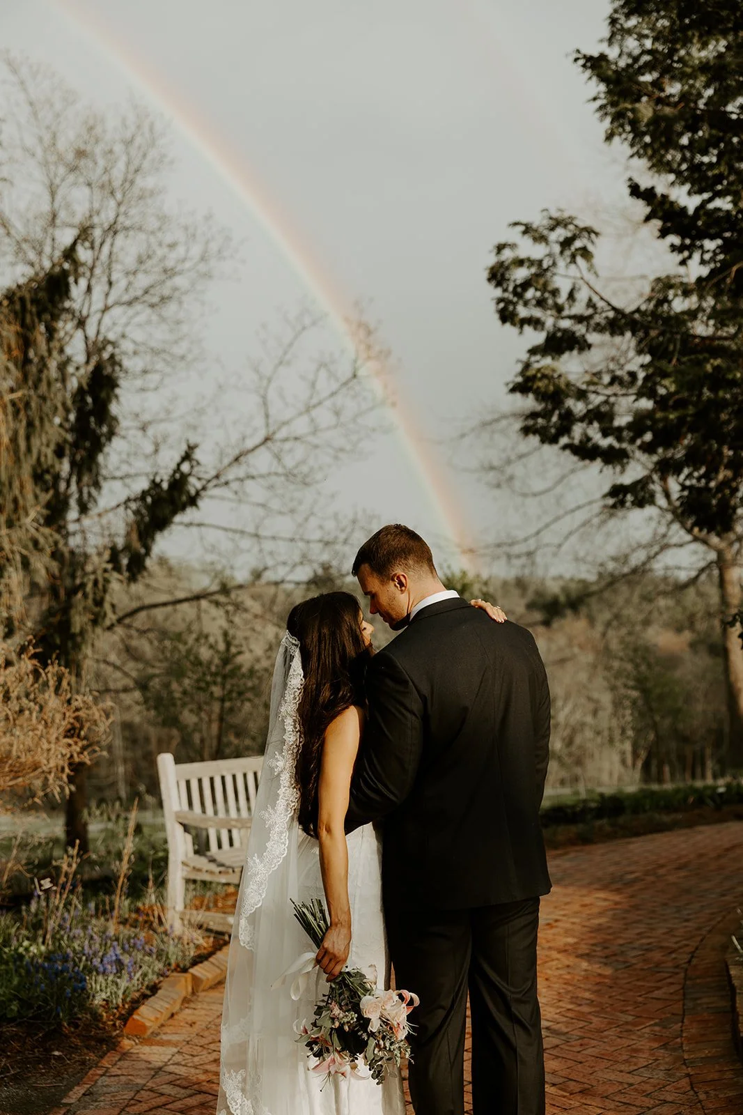A bride and groom taking elopement photos with a rainbow