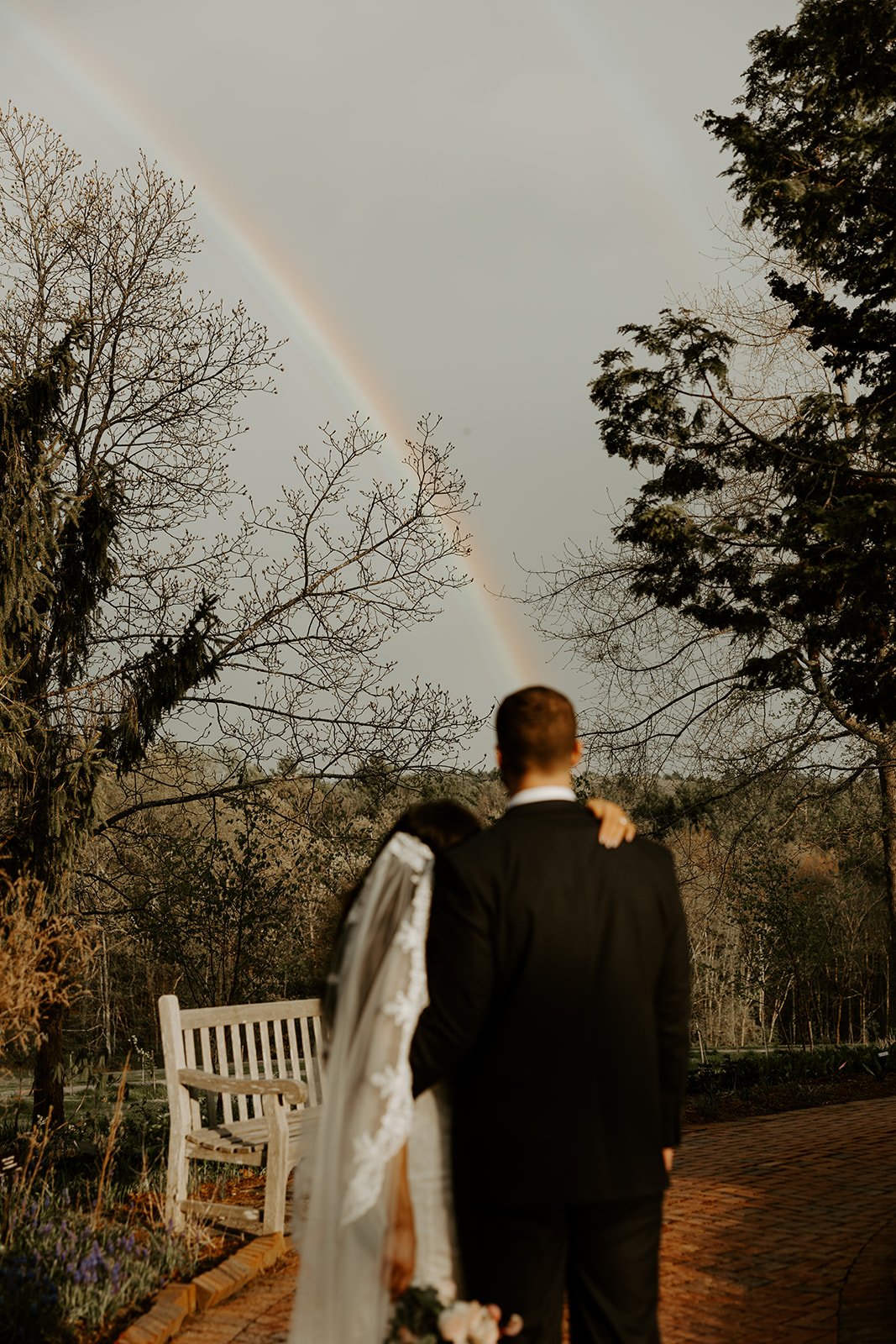 A bride and groom taking elopement photos with a rainbow