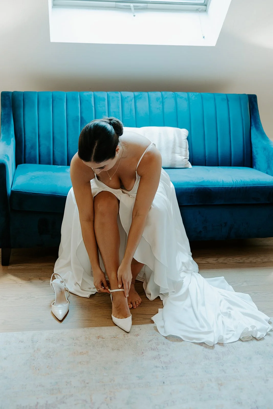 A bride putting on her shoes in the getting-ready spaces in the grove