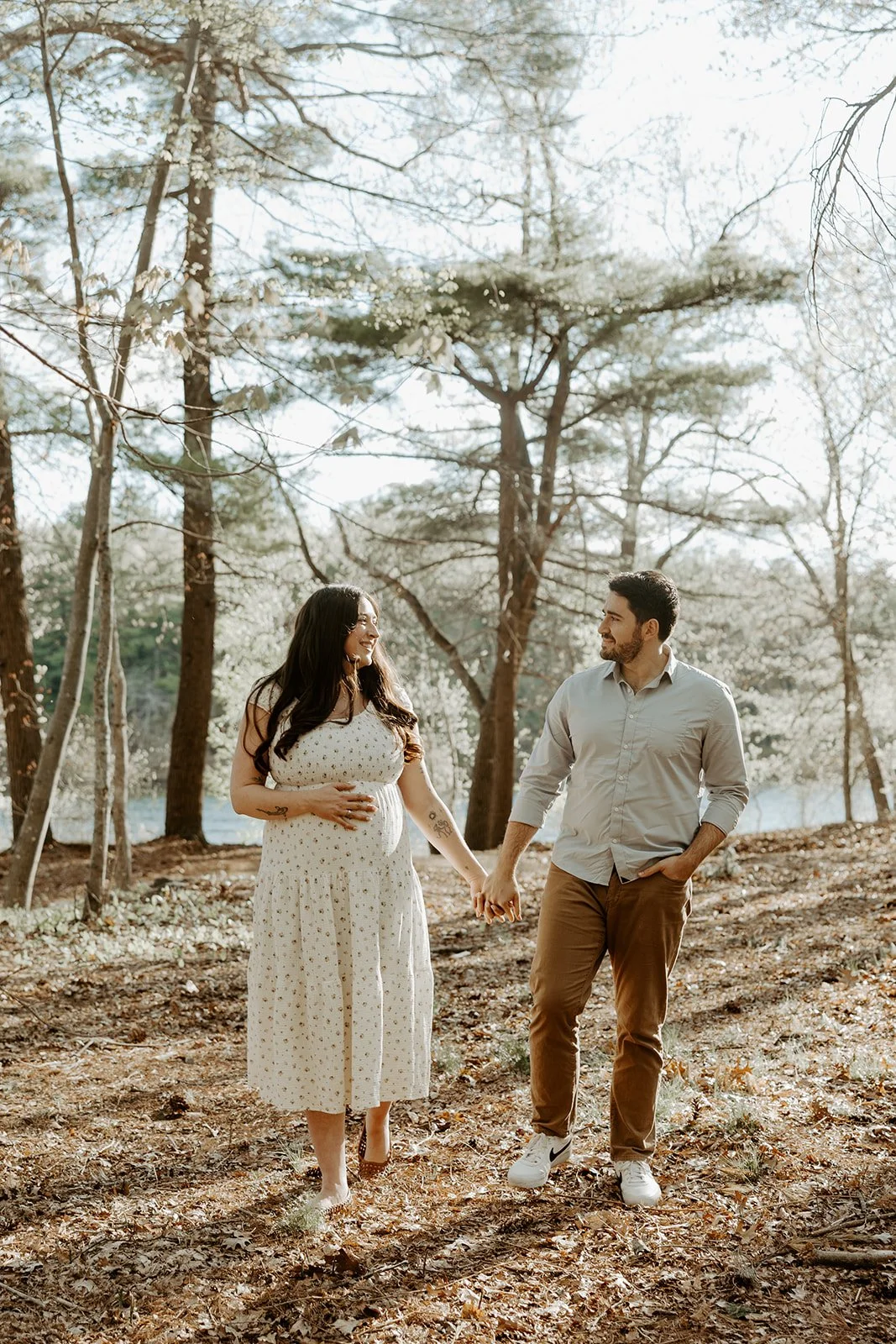 A couple walking through the woods at a maternity photoshoot