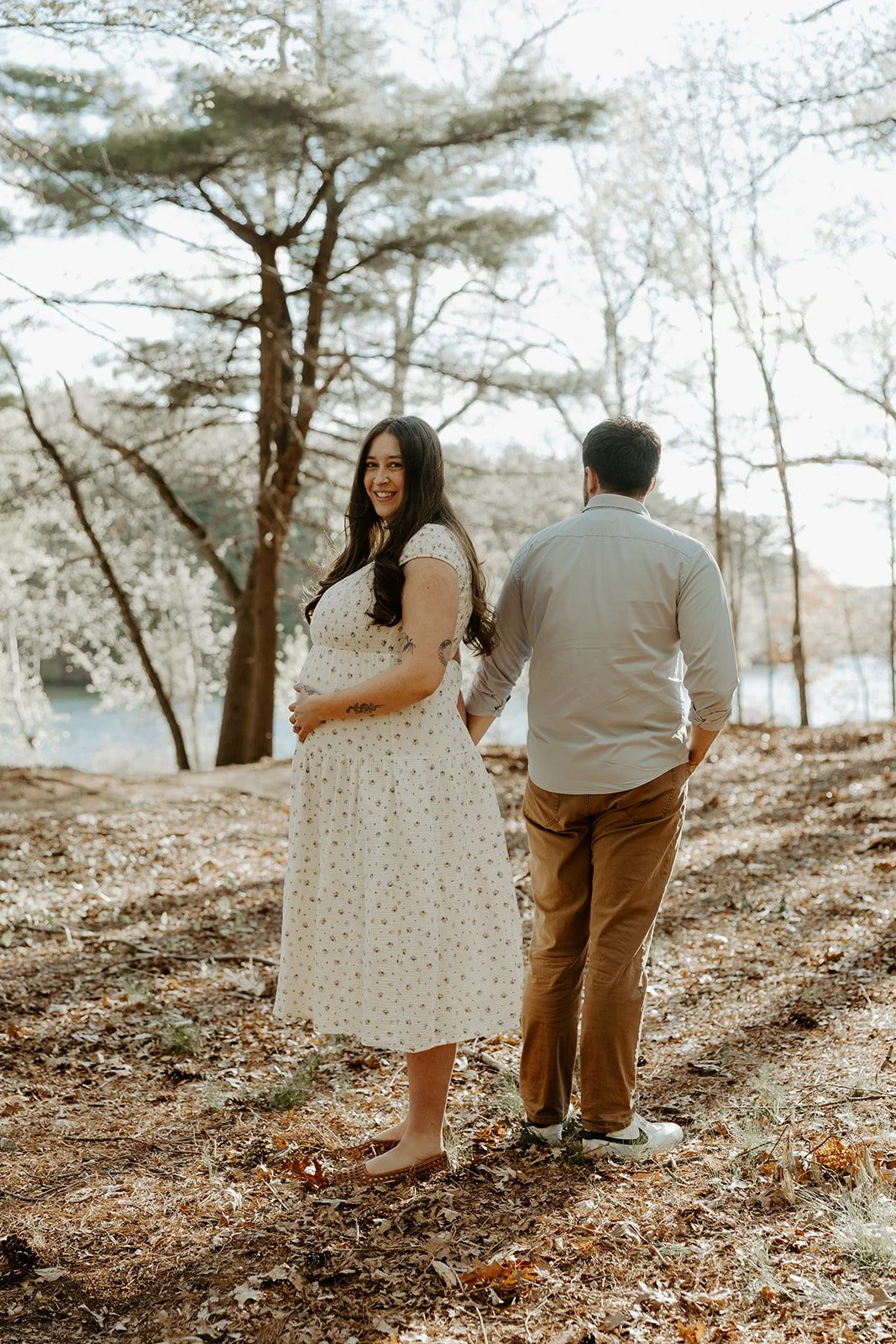 A couple walking through the woods at a maternity photoshoot