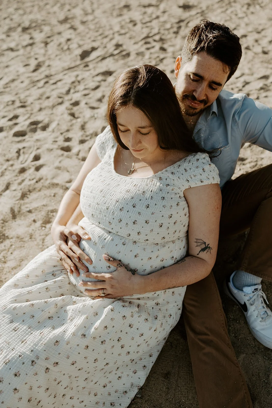 A couple taking beach maternity photos
