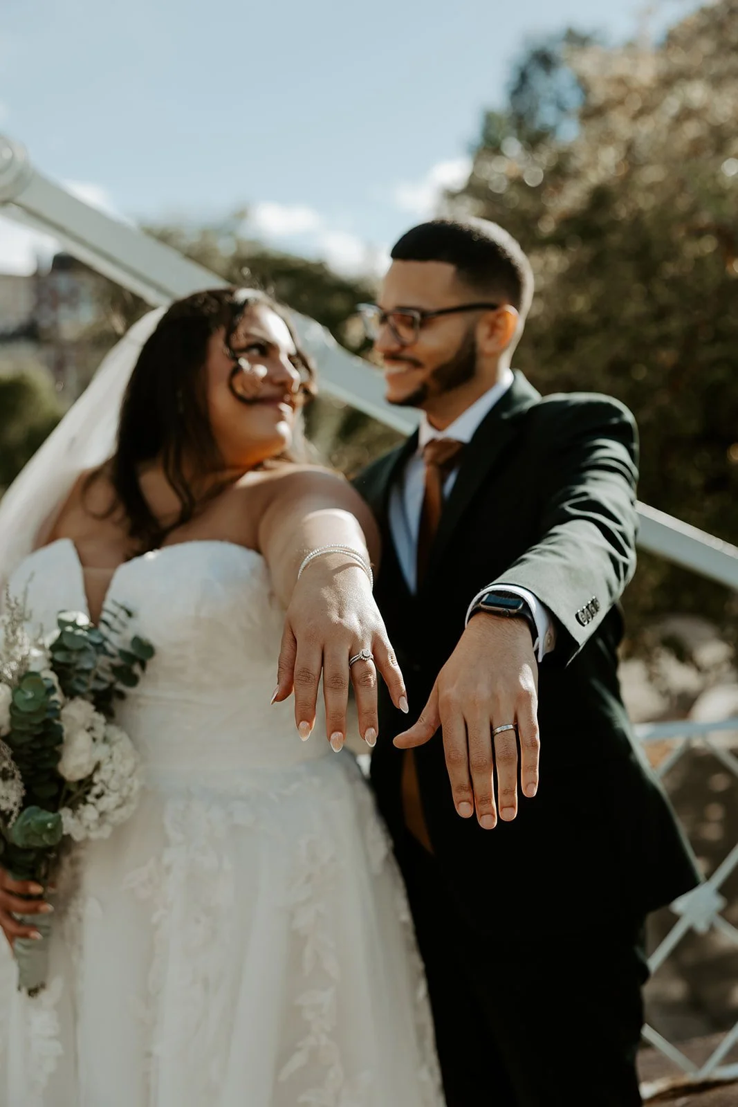 A bride and groom showing off their wedding rings