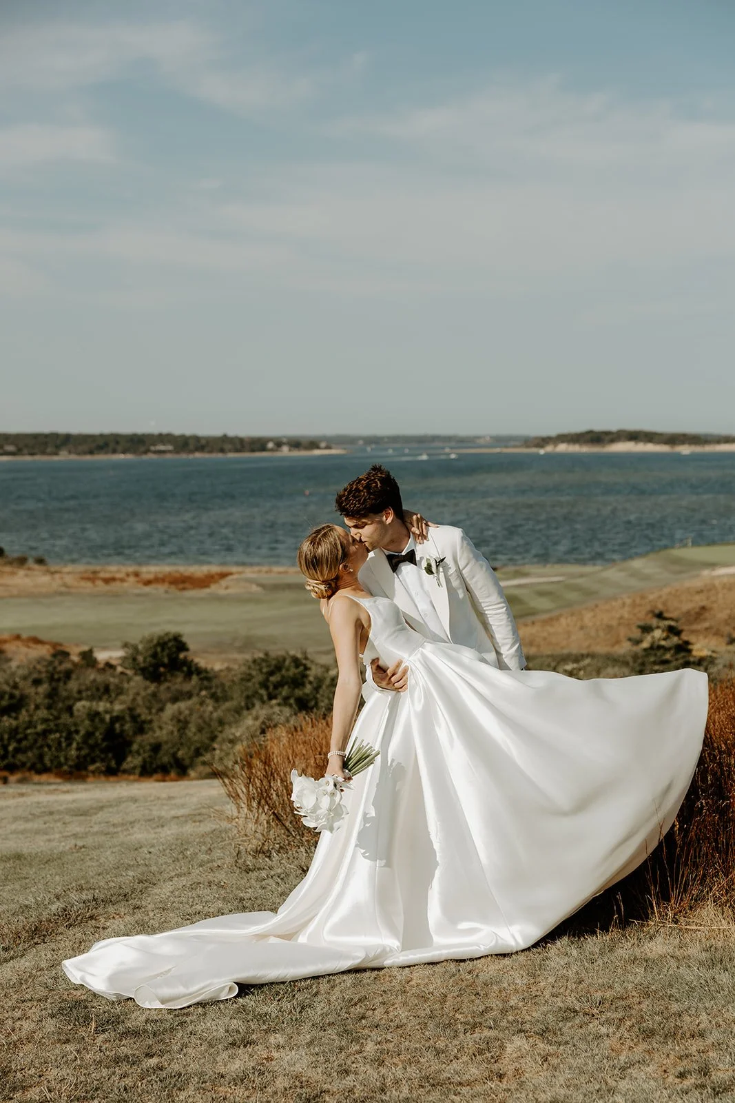 A bride and groom kissing in their coastal wedding setting