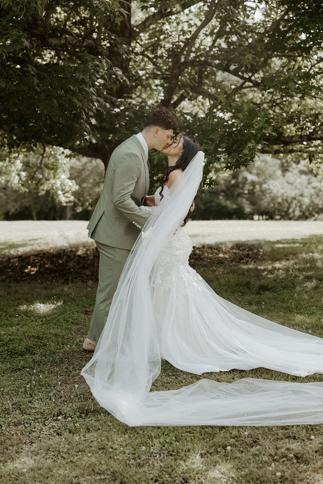 A bride and groom taking wedding photos under a tree
