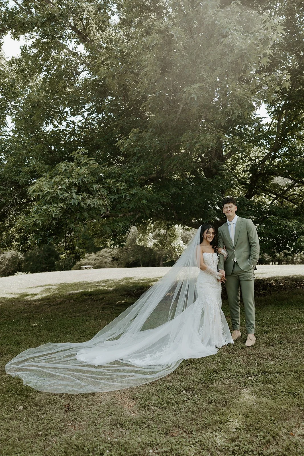 A bride and groom taking wedding photos under a tree