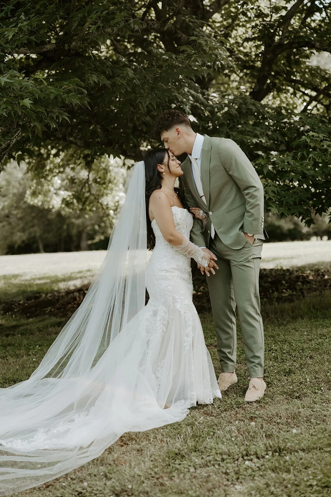 A bride and groom taking wedding photos under a tree