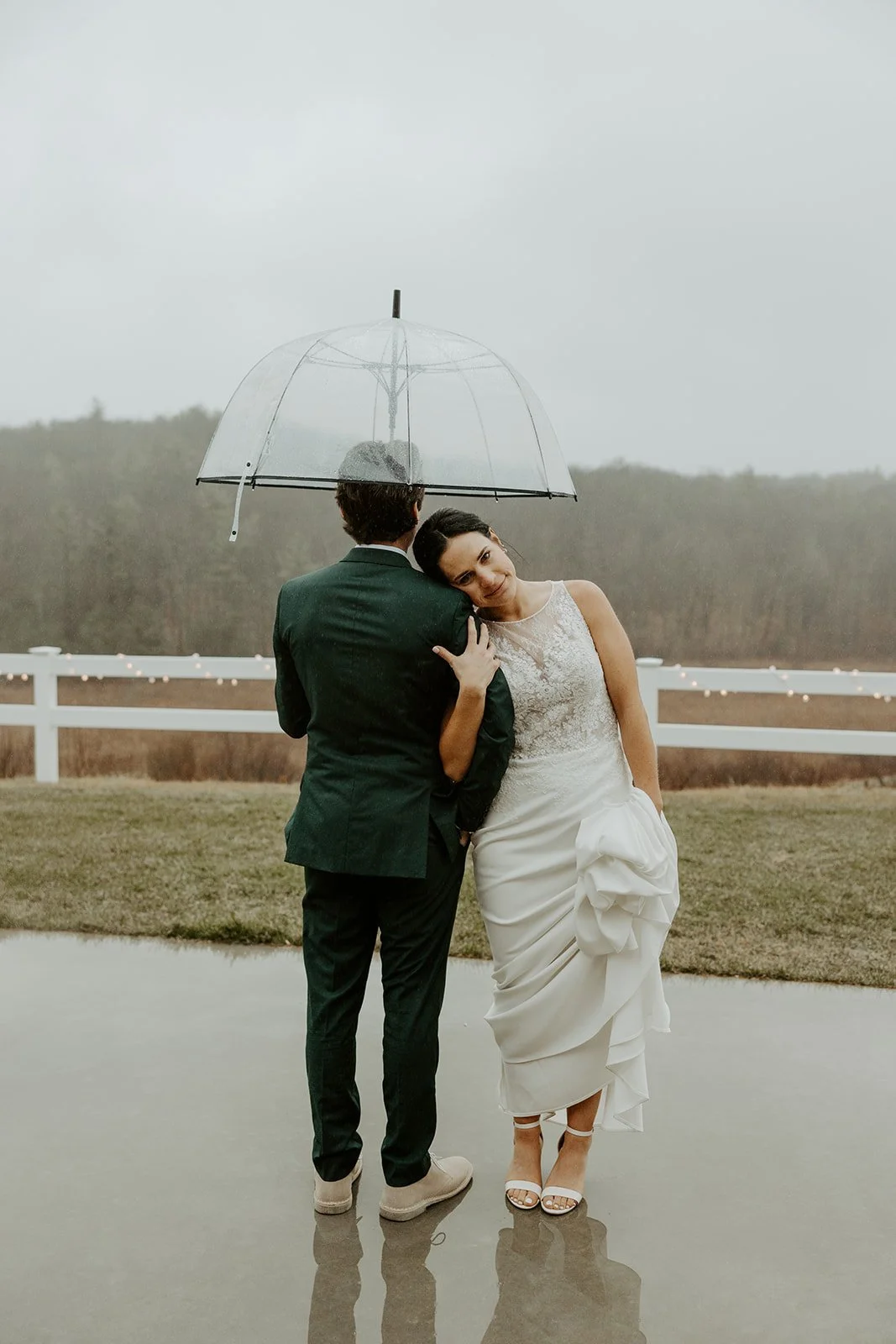 A bride and groom taking photos on their rainy wedding day