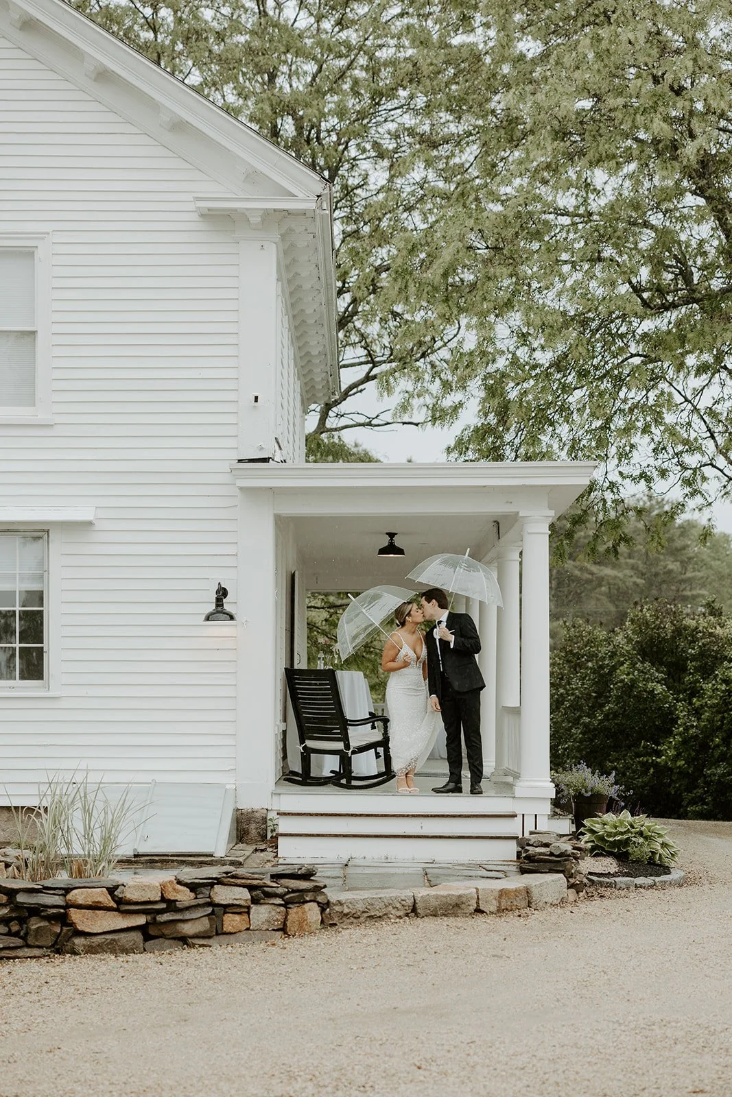 A bride and groom on the porch of their Maine wedding venue