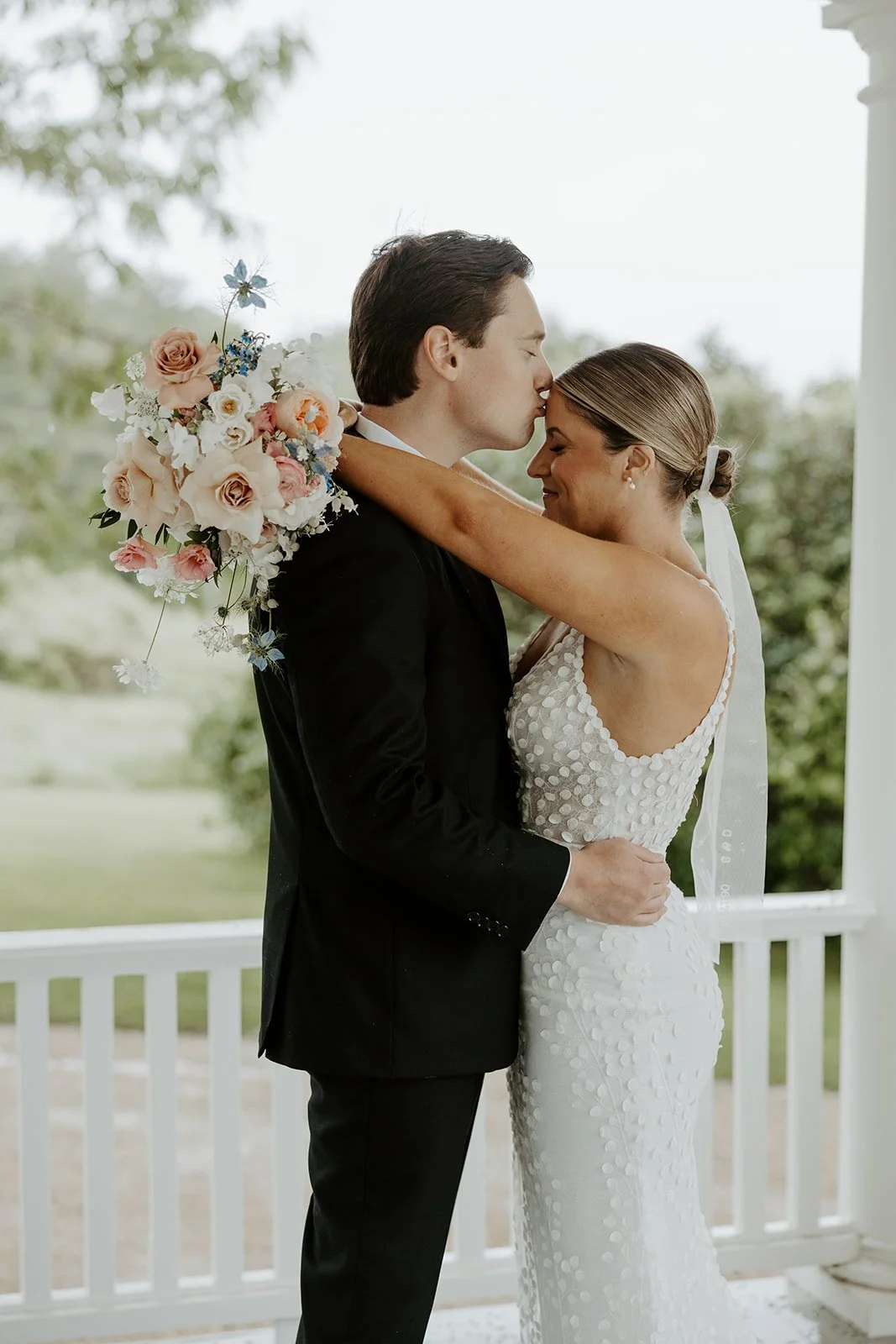 A bride and groom on the porch of their Maine wedding venue