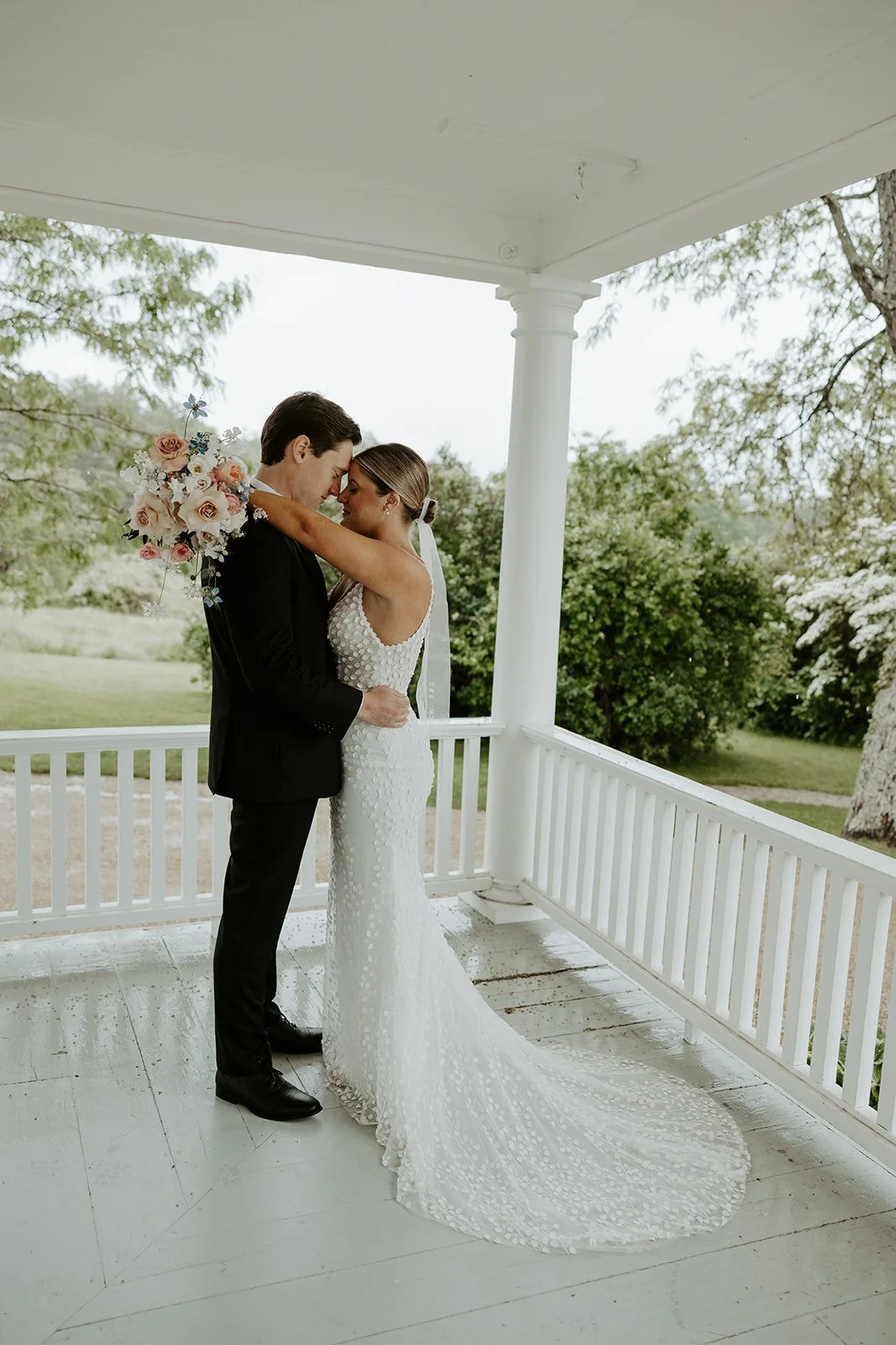 A bride and groom on the porch of their Maine wedding venue