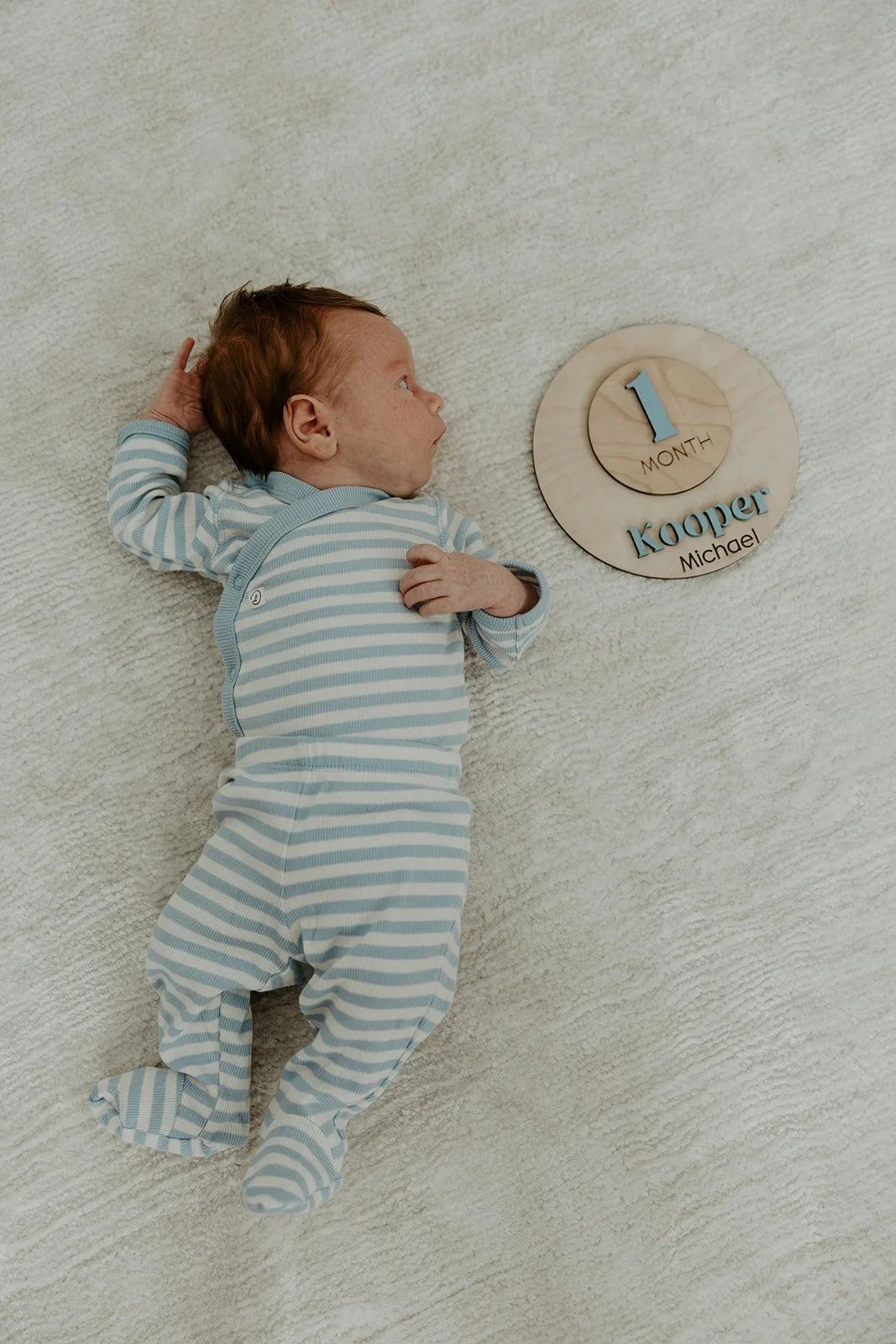 A baby with a one-month sign, by a Boston newborn photographer