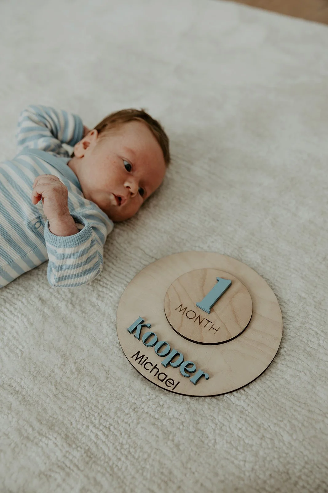 A baby with a one-month sign, by a Boston newborn photographer