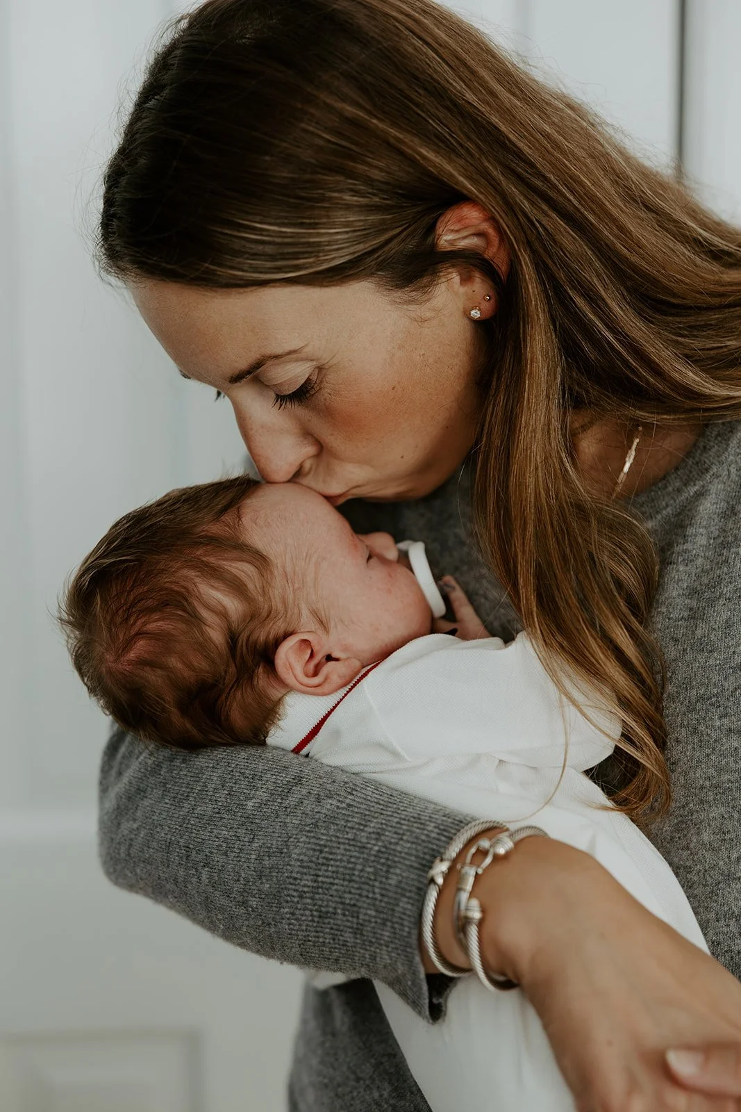 A mom kissing her newborn baby