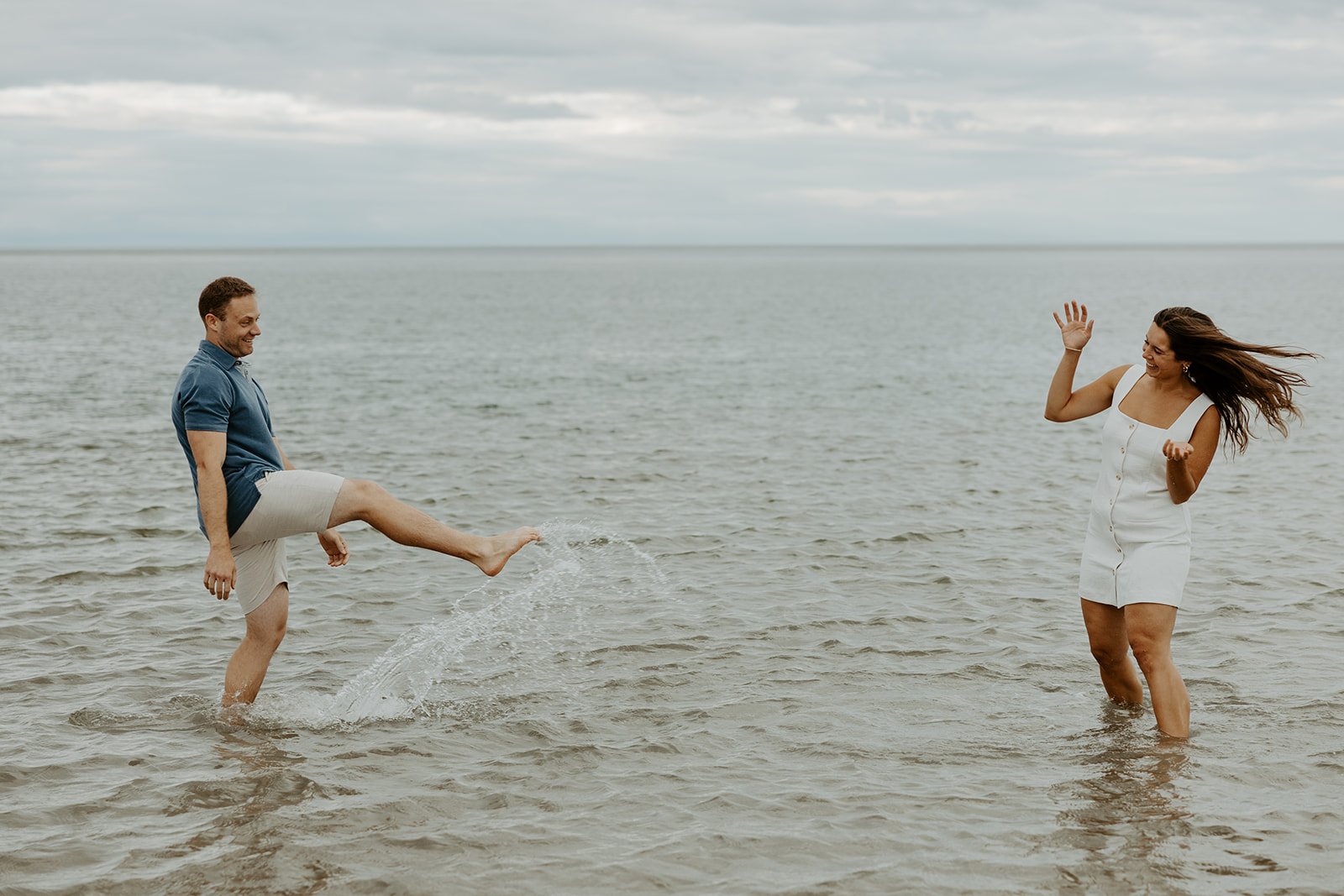 A couple playing in the ocean at their beach Massachusetts engagement photo location