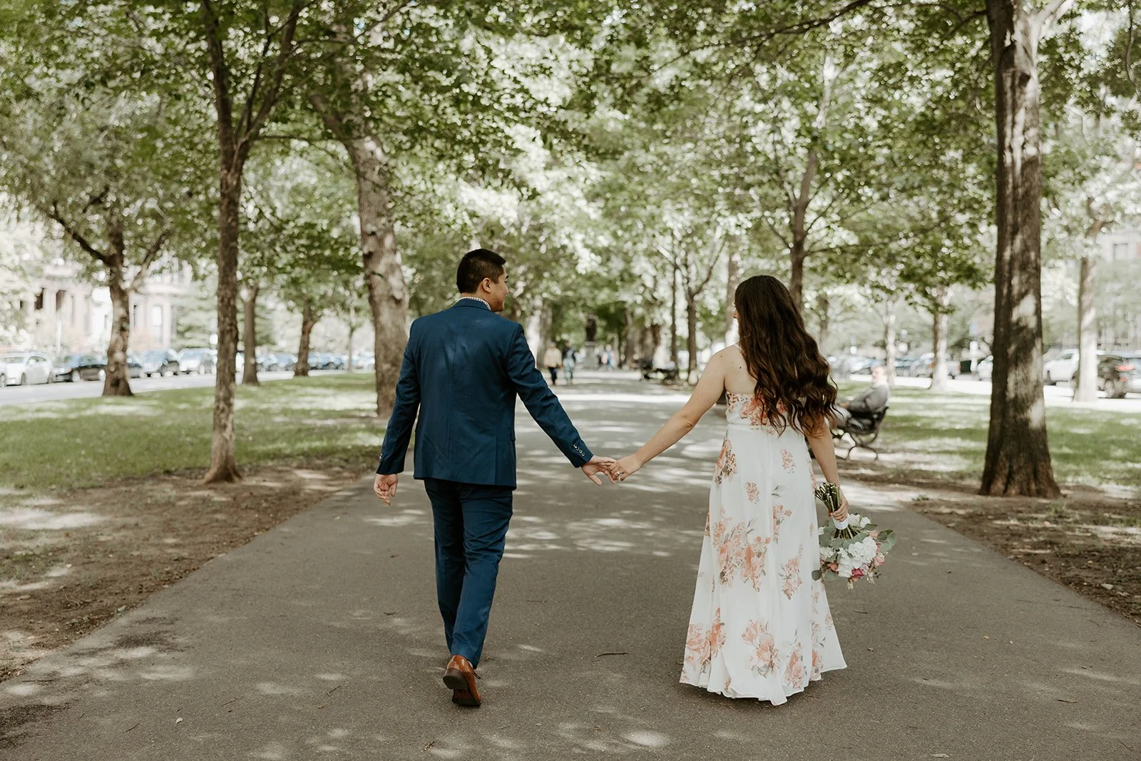 A wedding couple walking through a park after their Boston Public Library elopement