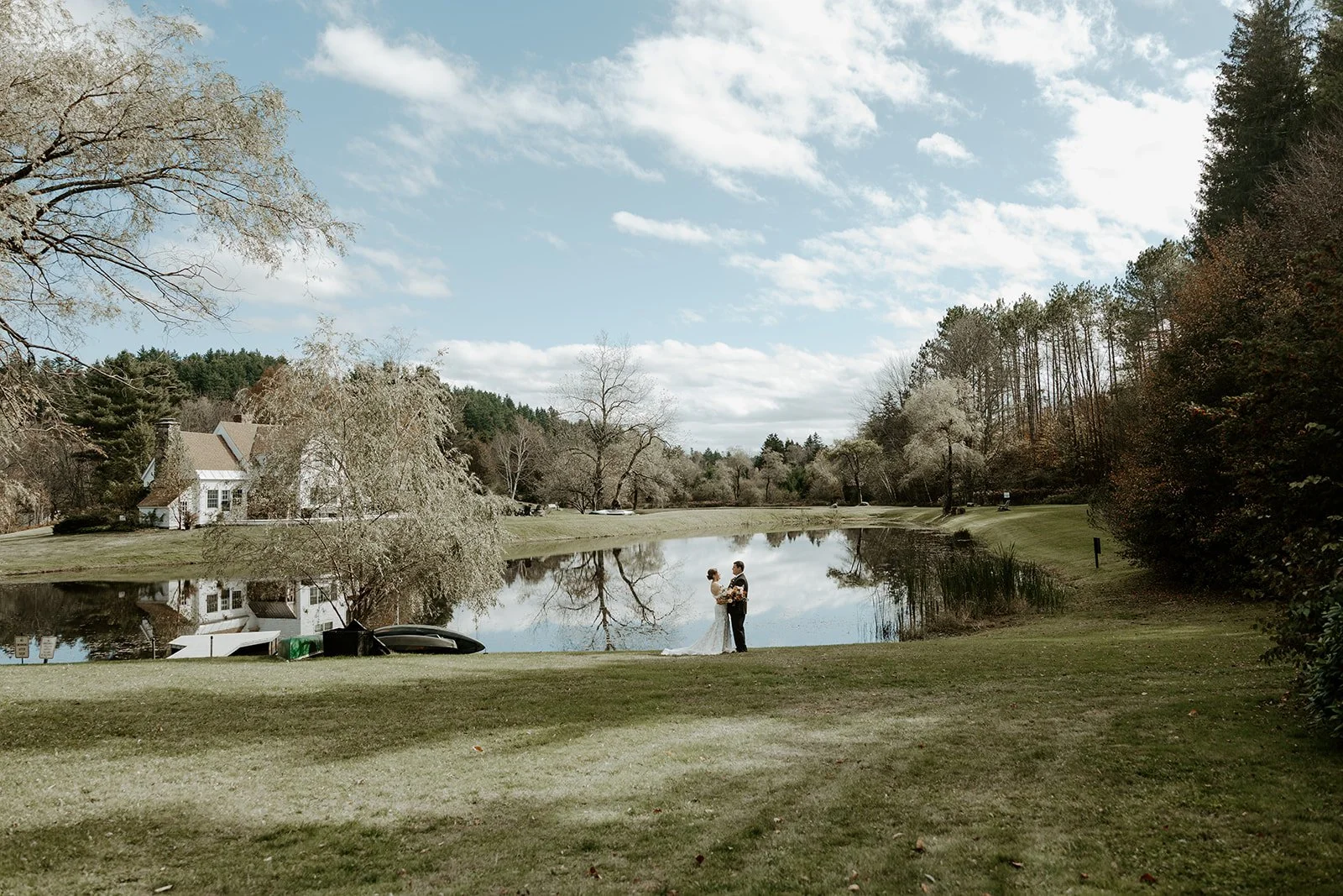 A bride and groom in front of a pond at their Vermont wedding venue