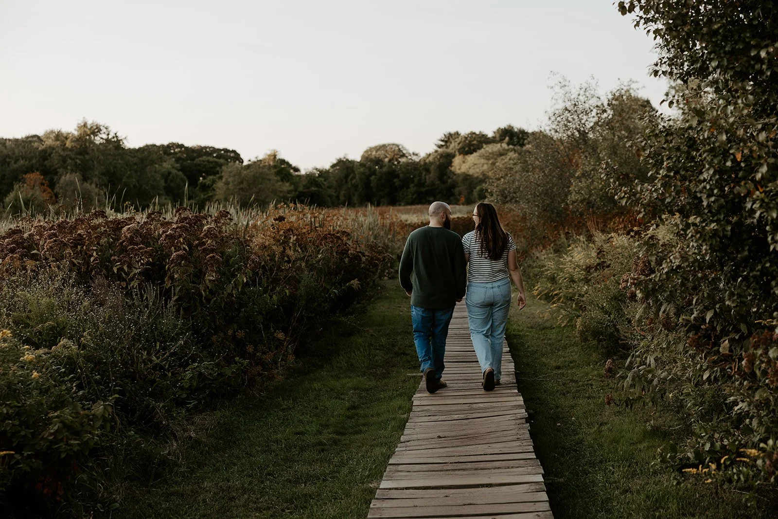 A couple walking in engagement photos at a Massachusetts engagement photo location, Rock MEadow