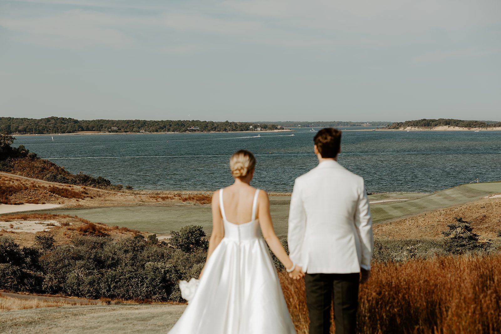 A bride and groom looking out at their coastal wedding setting
