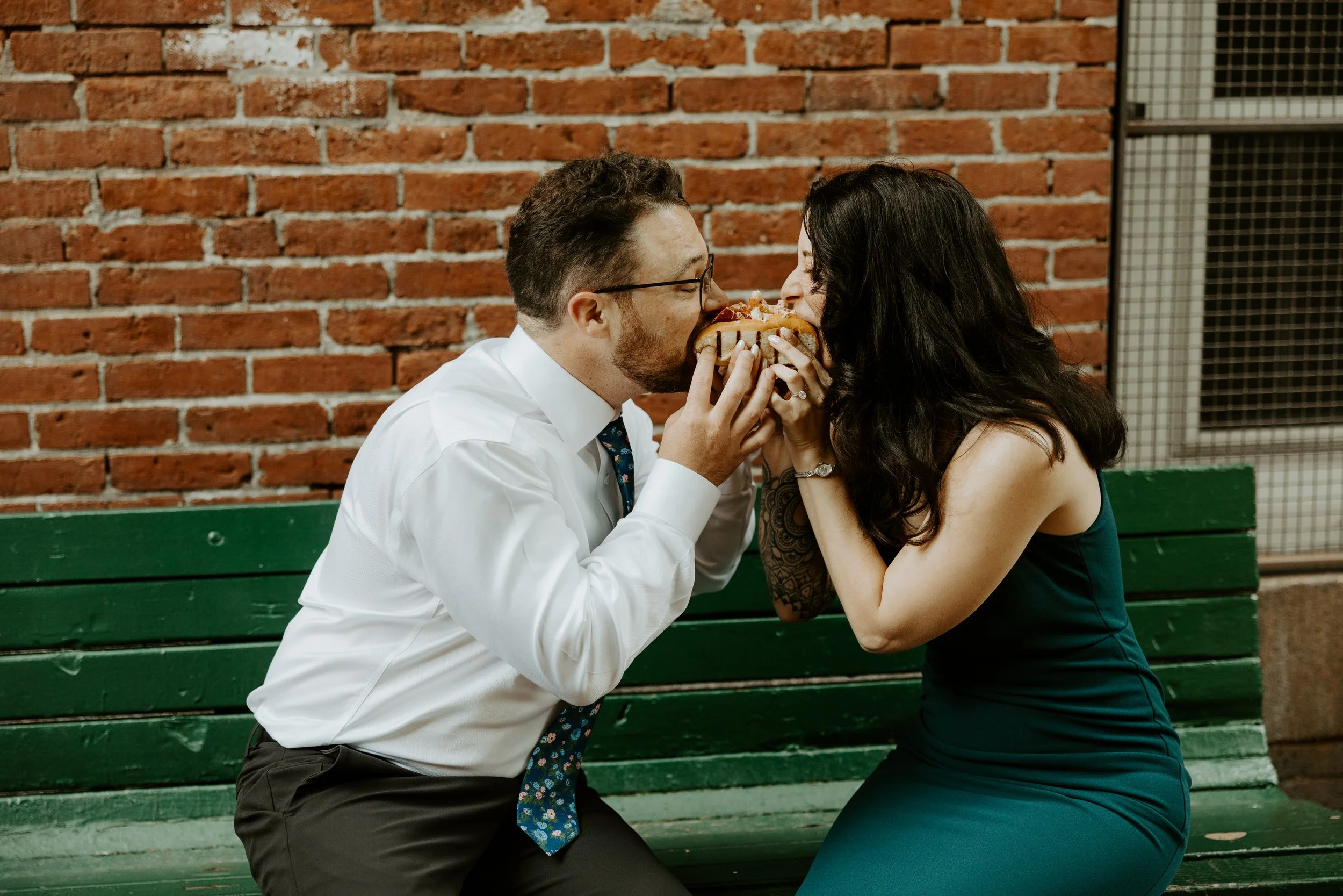 A couple eating a meatball sub from both ends during their engagement photoshoot