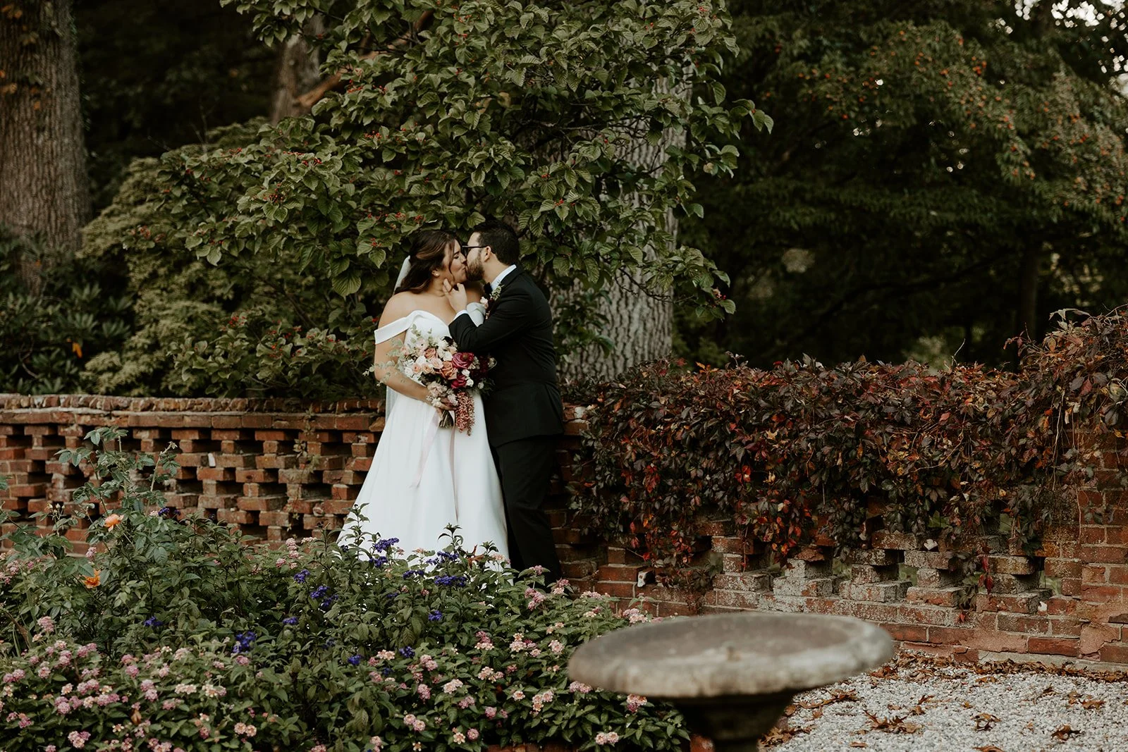 A bride and groom kissing in the gardens at The Bradley Estate