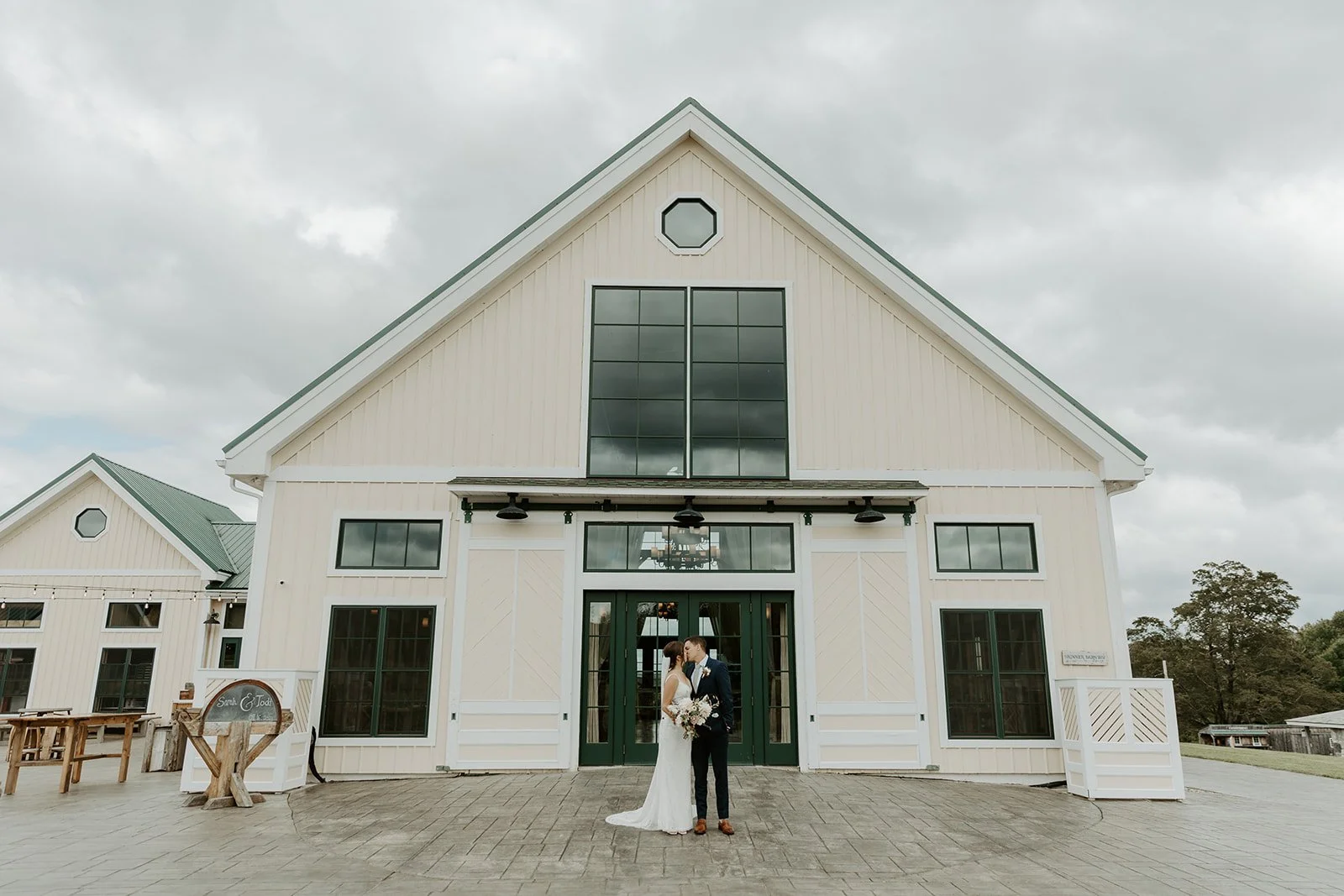 A couple kissing in front of the yellow barn at Valley View Farm