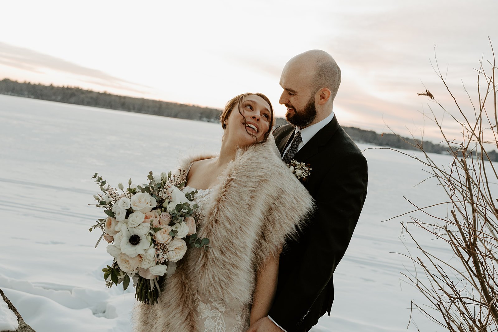 A bride and groom posing for winter sunset wedding photos