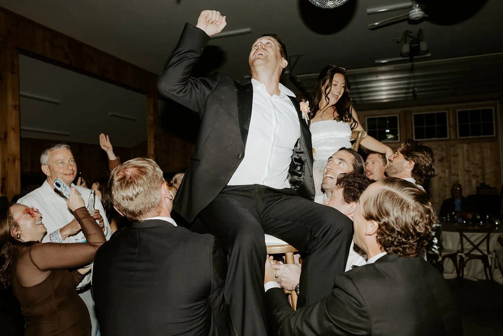 A bride and groom being lifted at a wedding reception