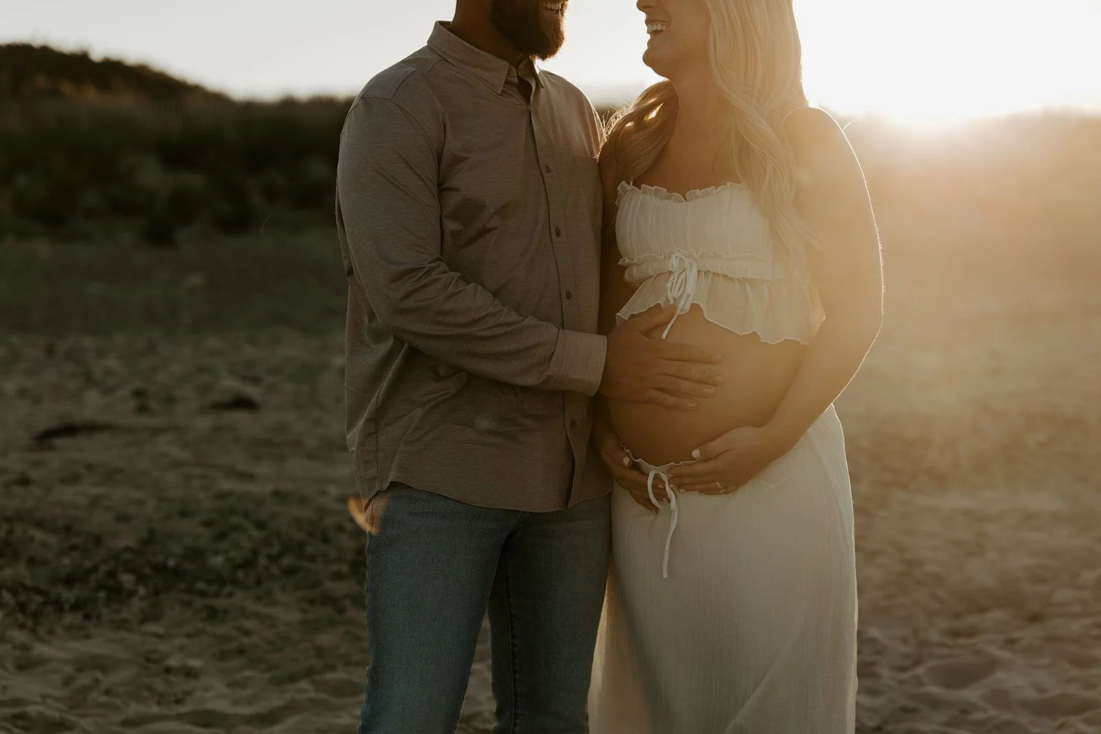 A Couple laughing during beach maternity photos