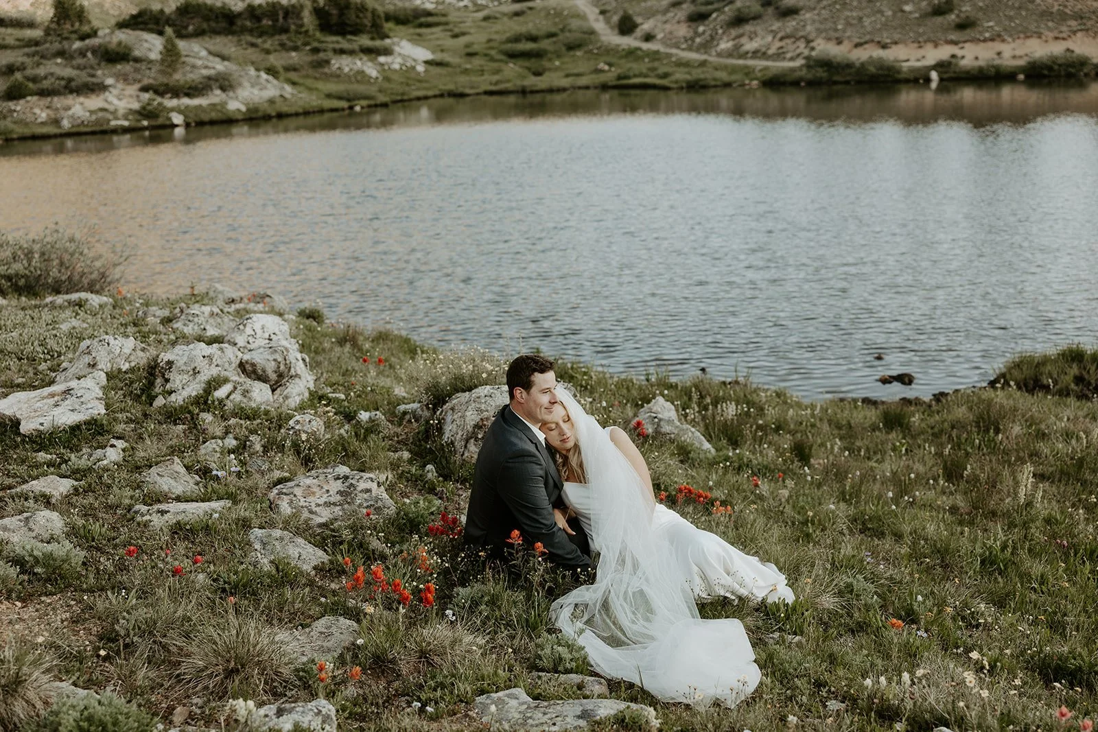 A couple posing for wedding photos by a lake