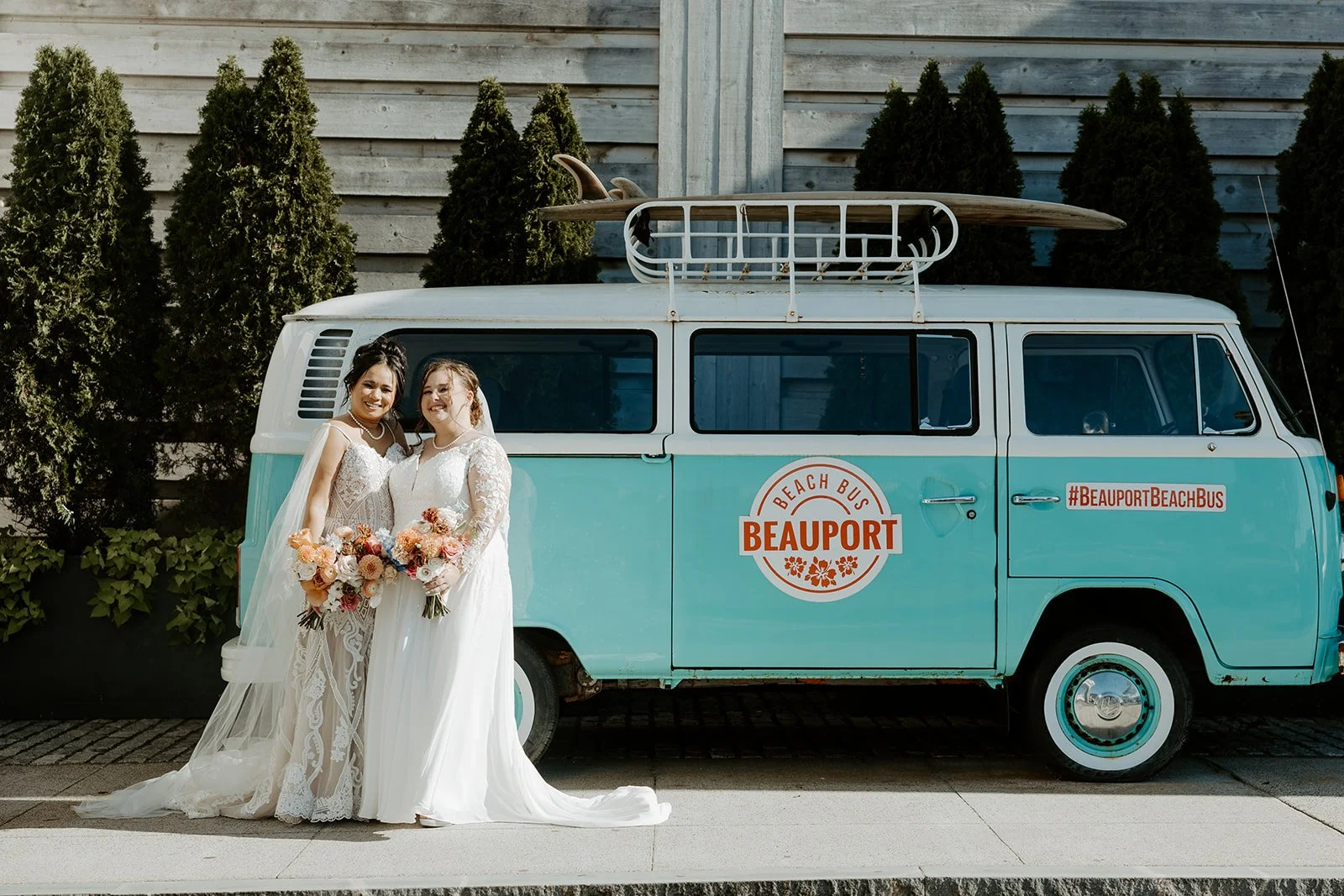 Two brides posing for wedding photos in front of a Volkswagen bus
