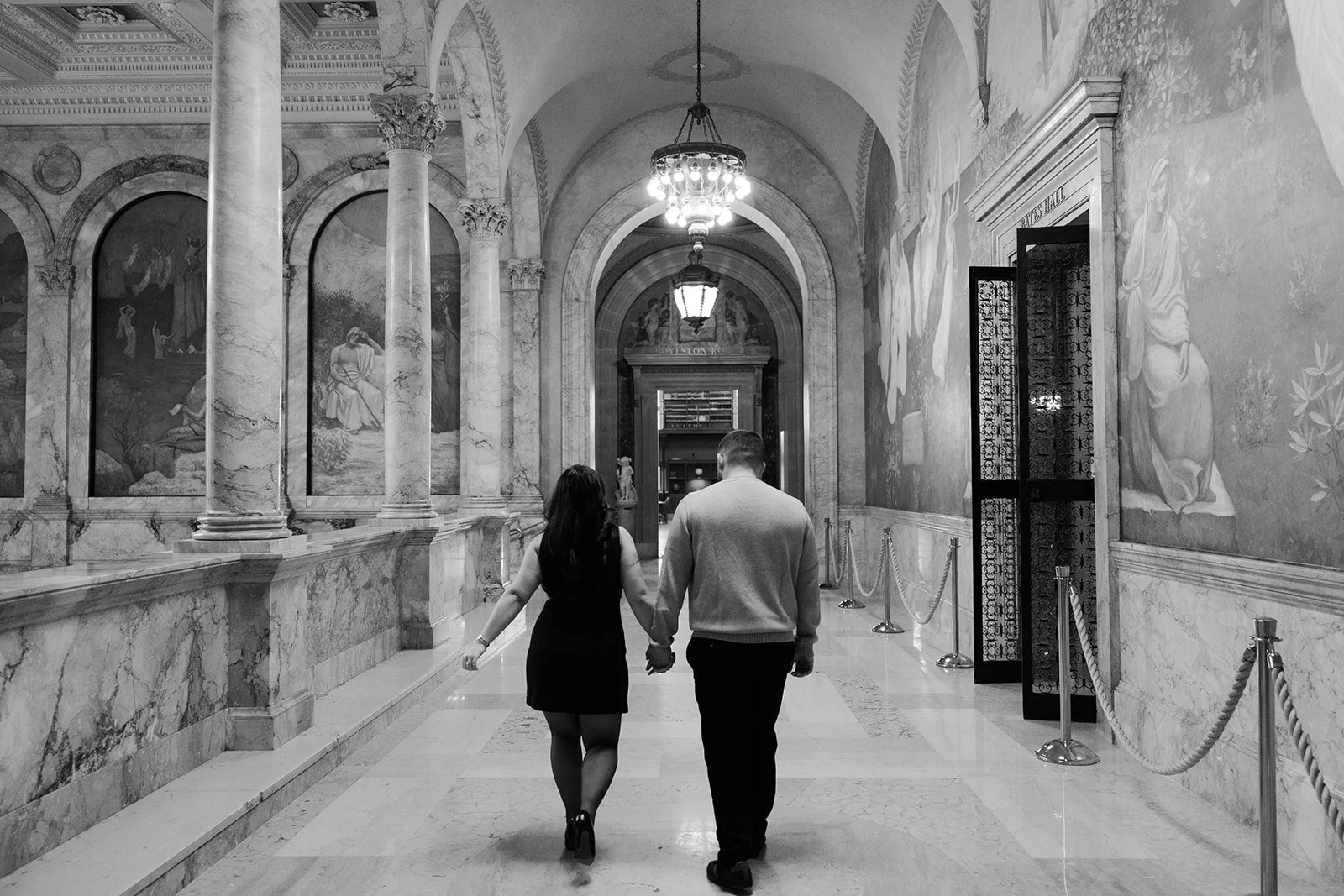 A couple walking in the hallway of the Boston Public Library for engagement photos
