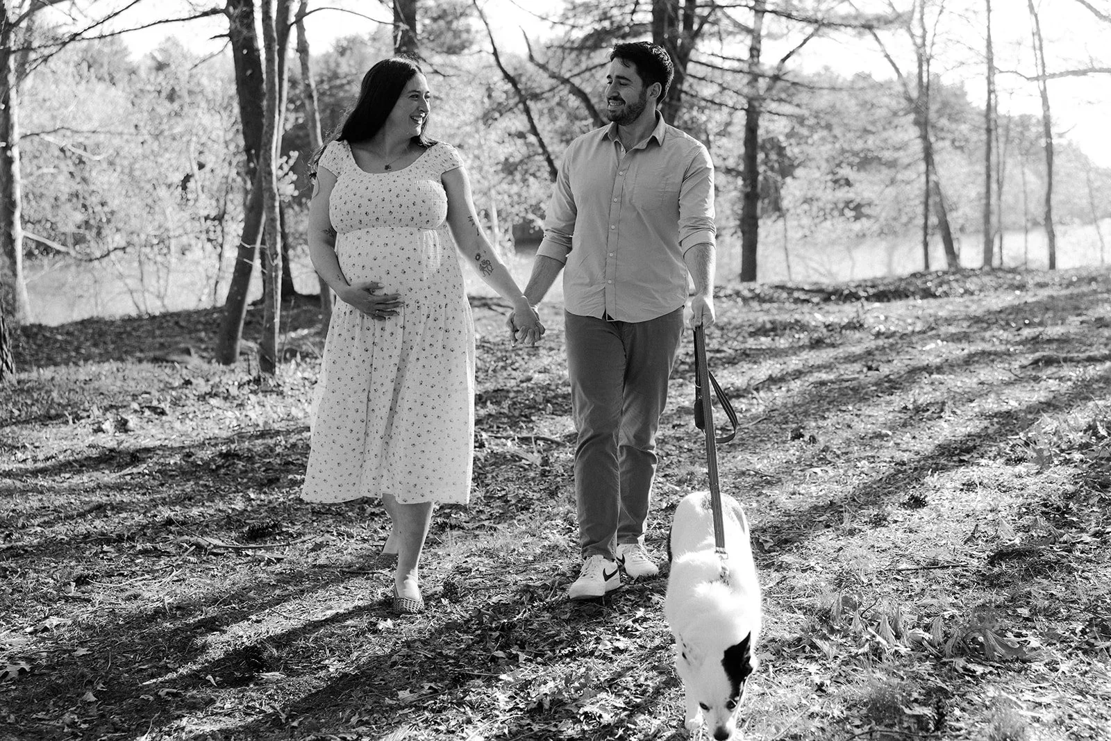 A couple walking through the woods during a maternity photoshoot