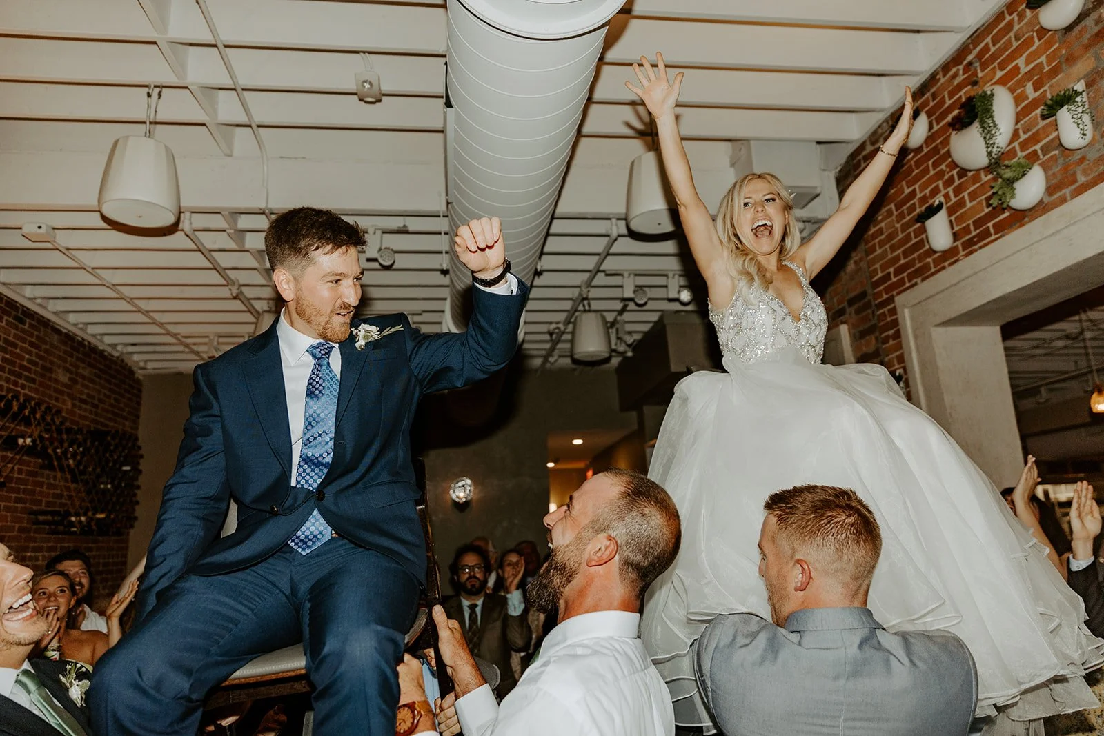 A couple being lifted and cheering at their restaurant wedding reception