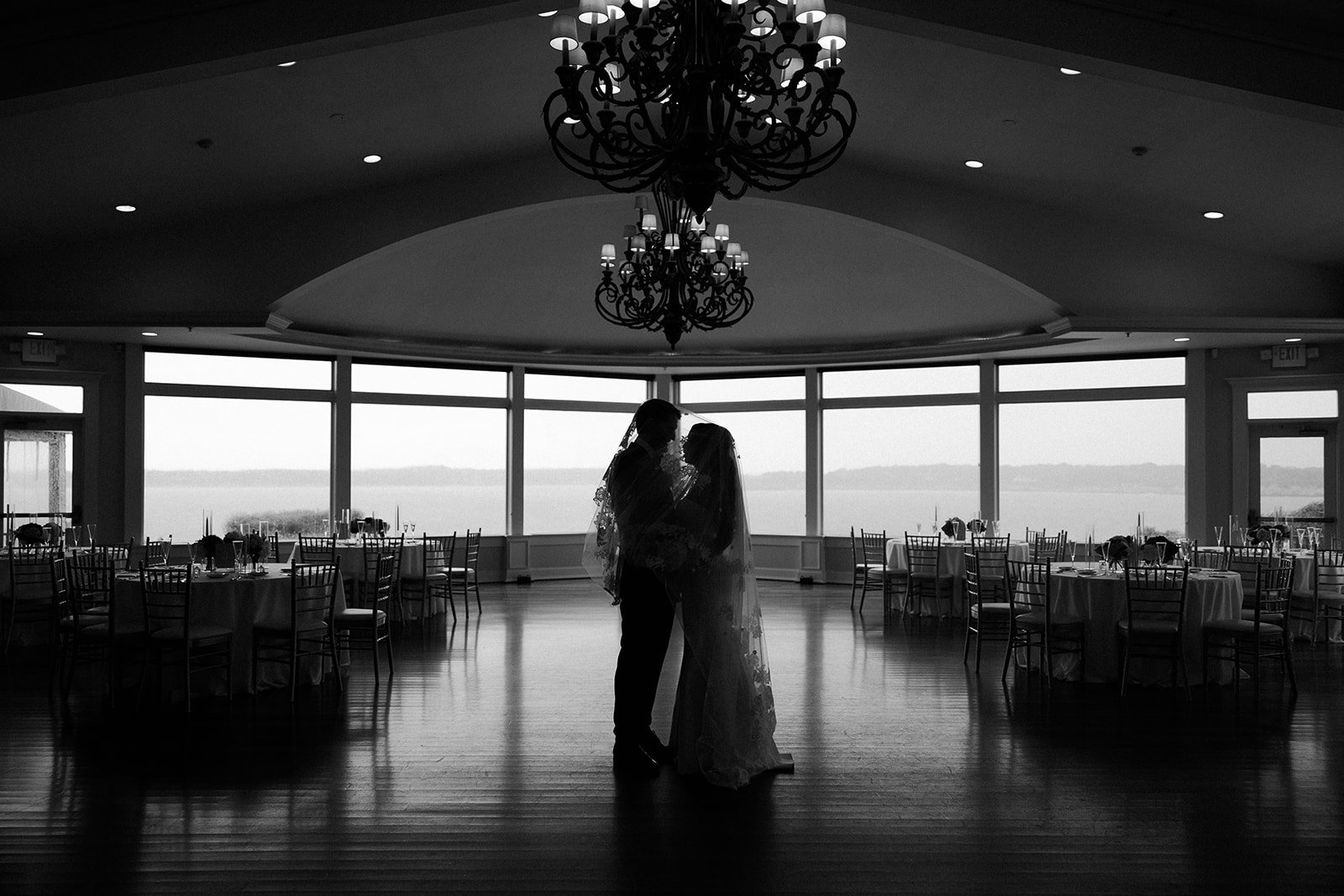 A black and white photo of a bride and groom inside of their empty wedding reception space