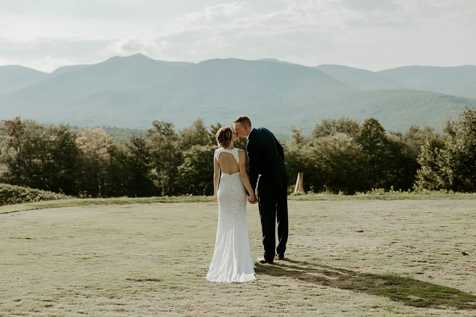 A bride and groom kissing in front of mountains at their Maine wedding venue