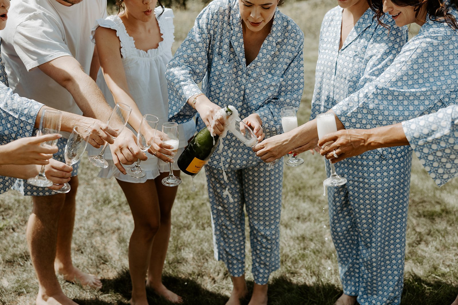 A bride and bridesmaids popping a champagne bottle