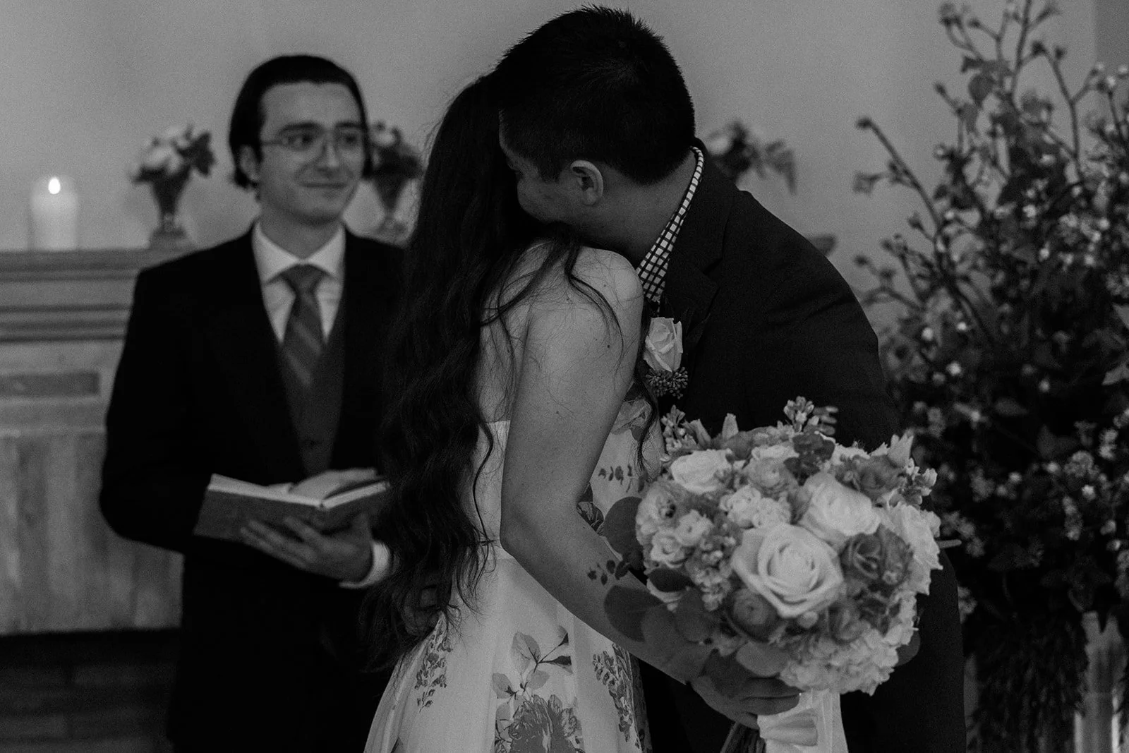 A black and white candid wedding photo of a bride and groom hugging at their Boston Public Library wedding ceremony