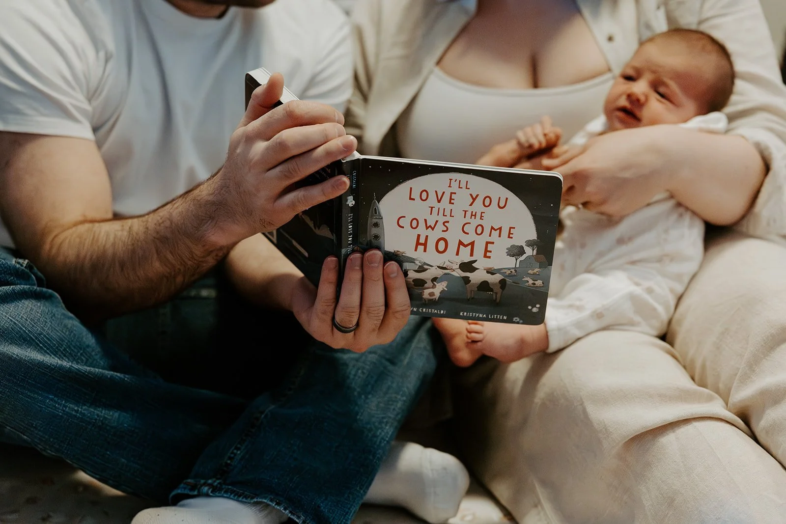 Parents reading a baby a book during newborn photos
