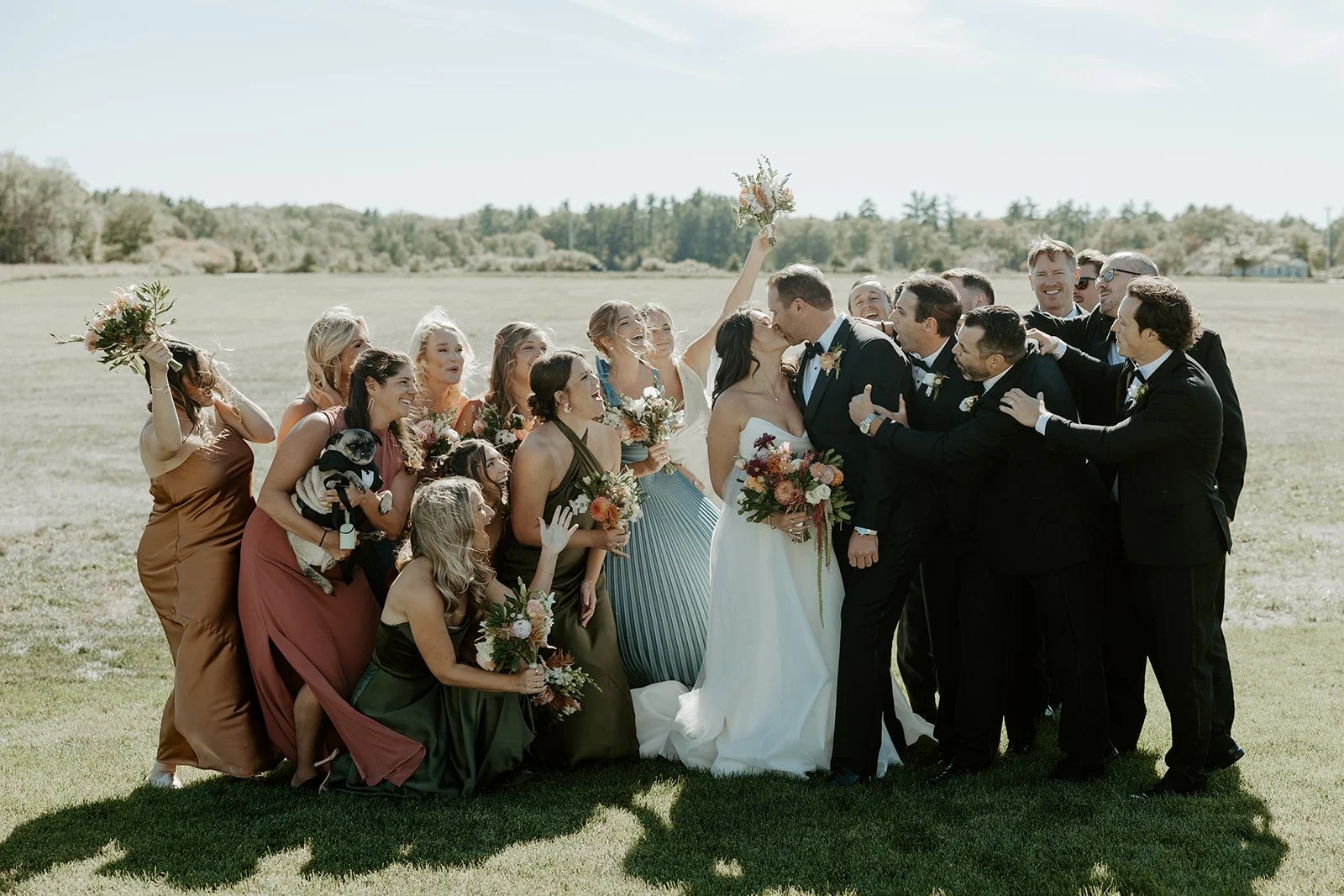 A wedding party cheering while a bride and groom kiss