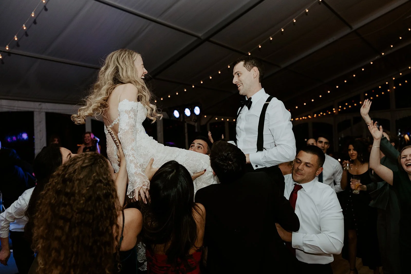A bride and groom being lifted at their wedding reception