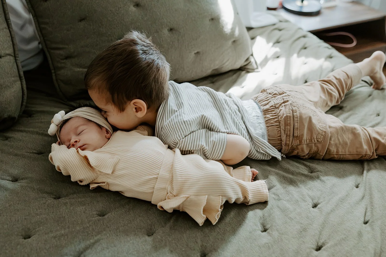 A brother kissing his new baby sibling in newborn photos